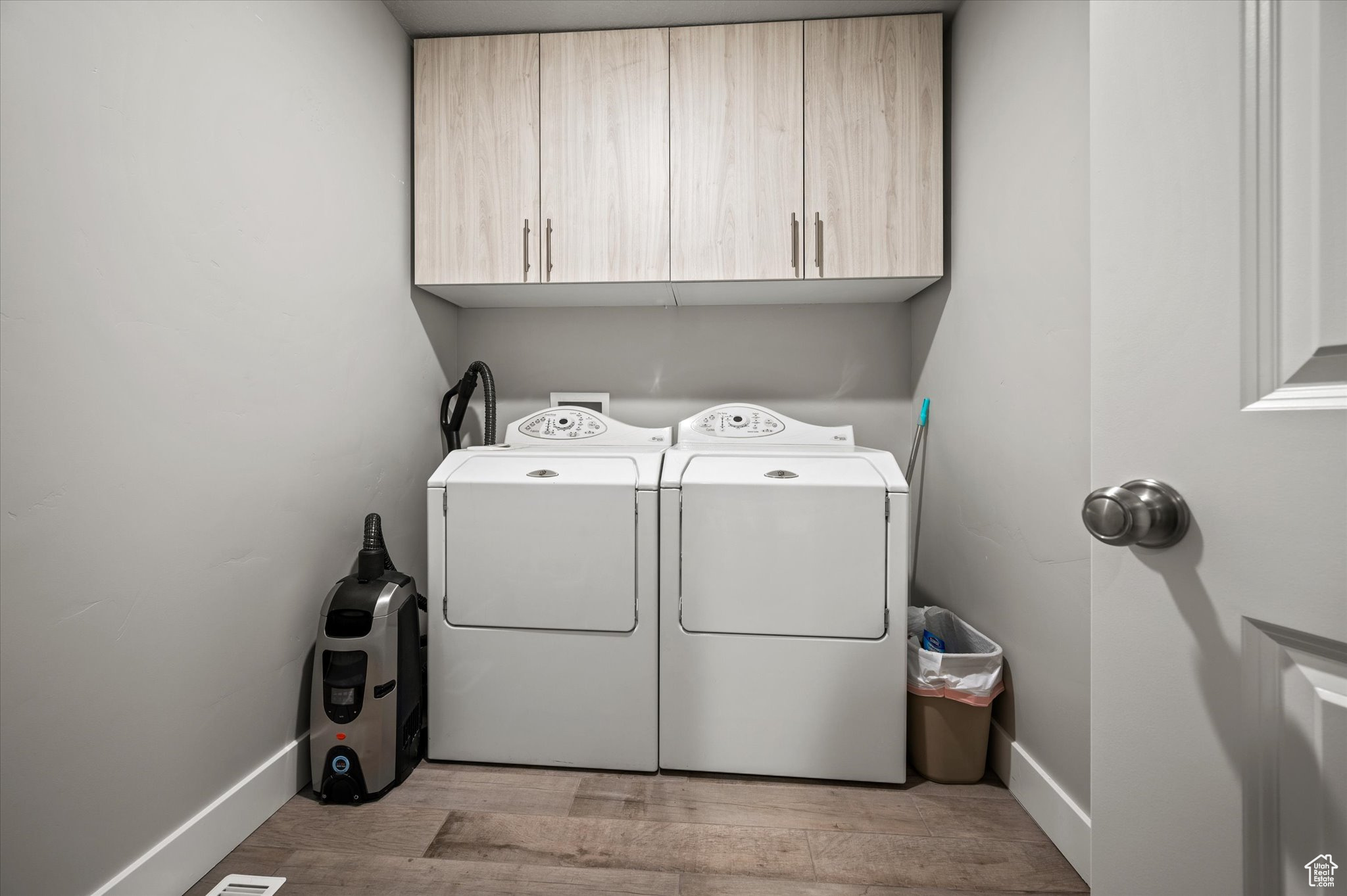 Laundry area featuring washer and dryer, cabinets, and light wood-type flooring