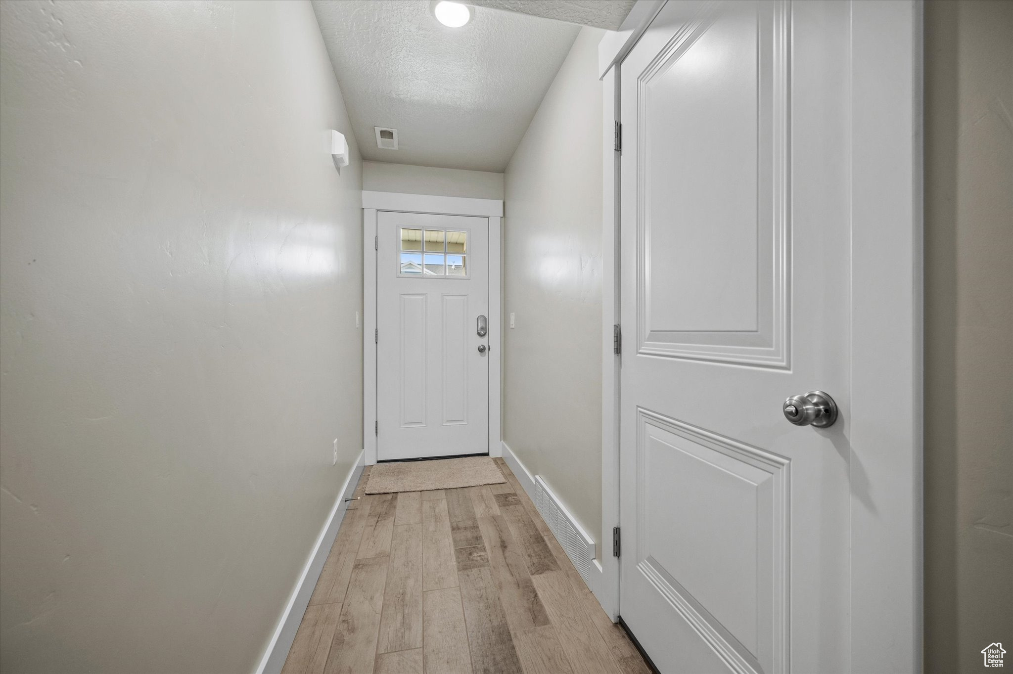 Entryway with a textured ceiling and light hardwood / wood-style flooring