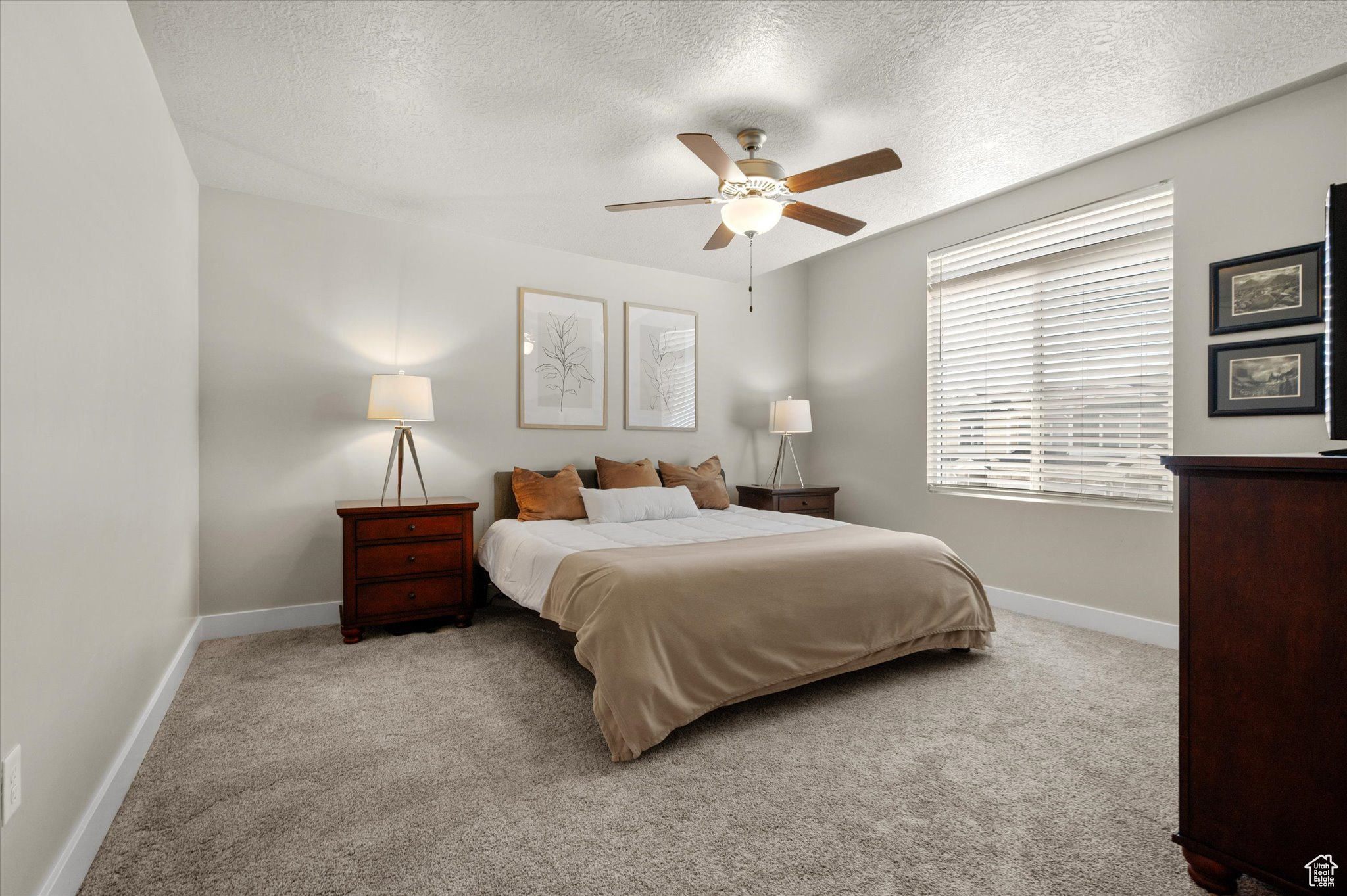 Bedroom featuring ceiling fan, light carpet, and a textured ceiling