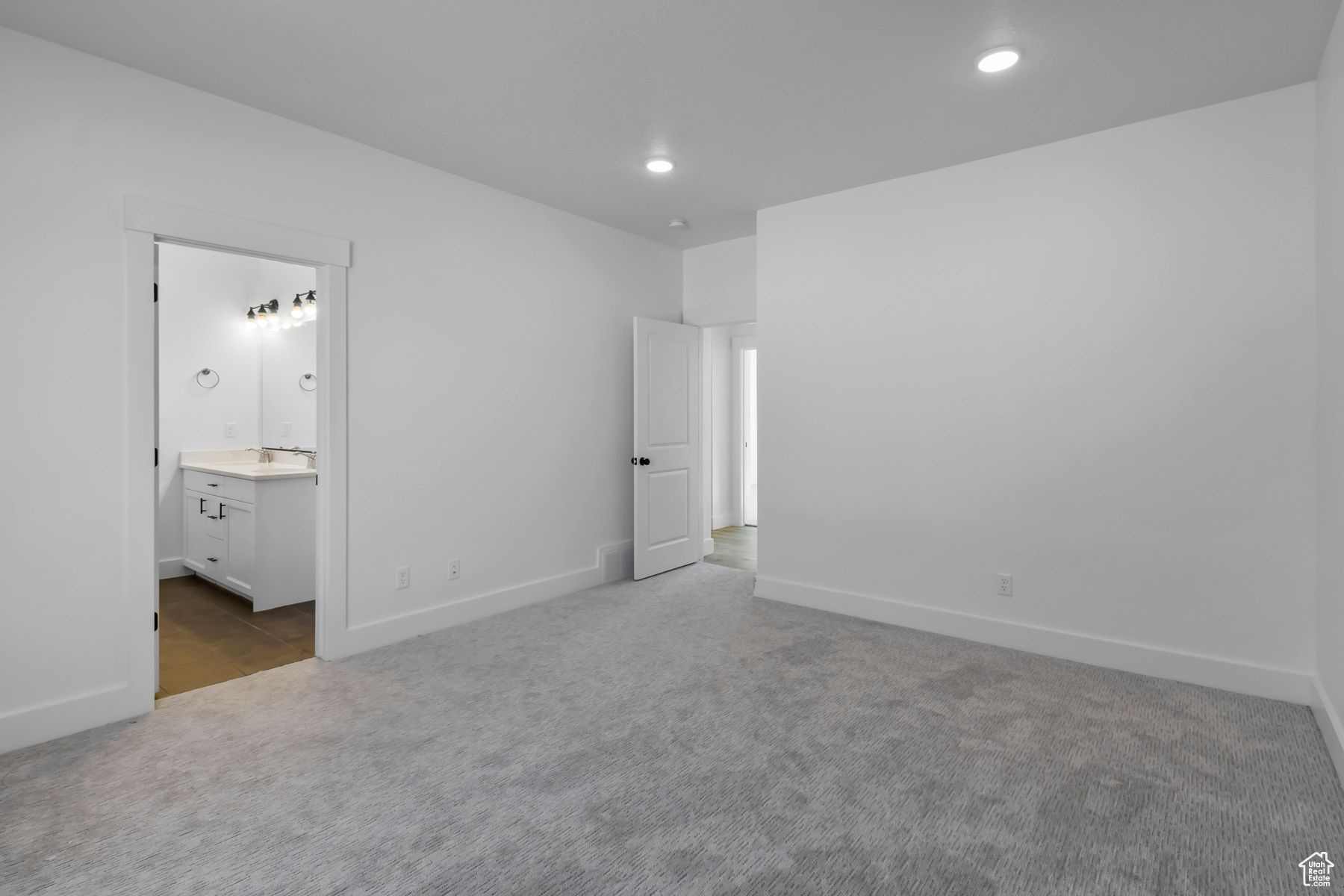 Unfurnished bedroom featuring sink, carpet floors, and ensuite bath