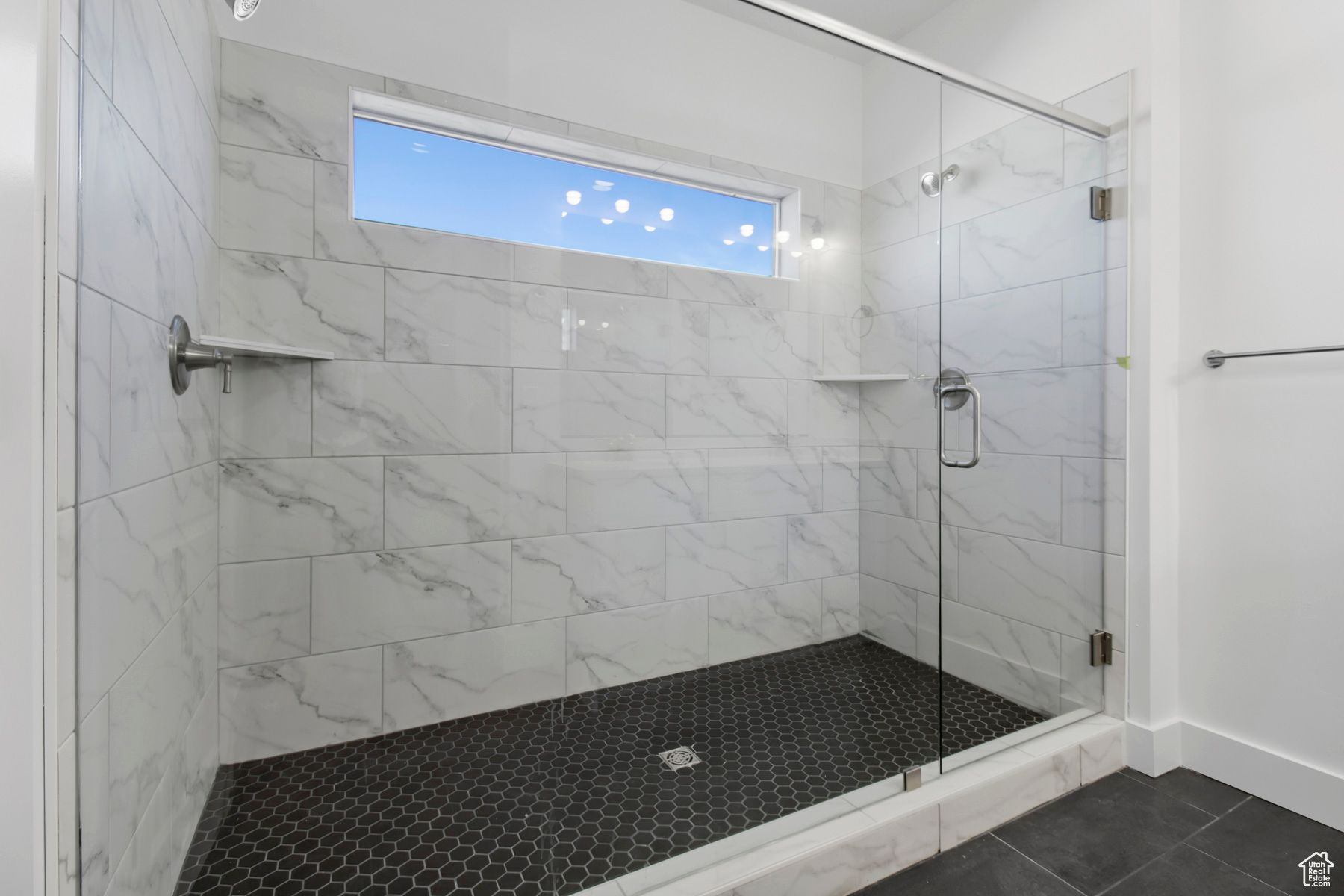 Bathroom featuring a shower with door and tile patterned flooring