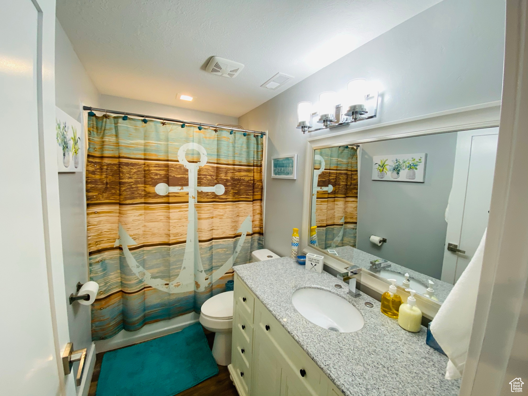 Full bathroom featuring toilet, vanity, and shower / bathtub combination with curtain