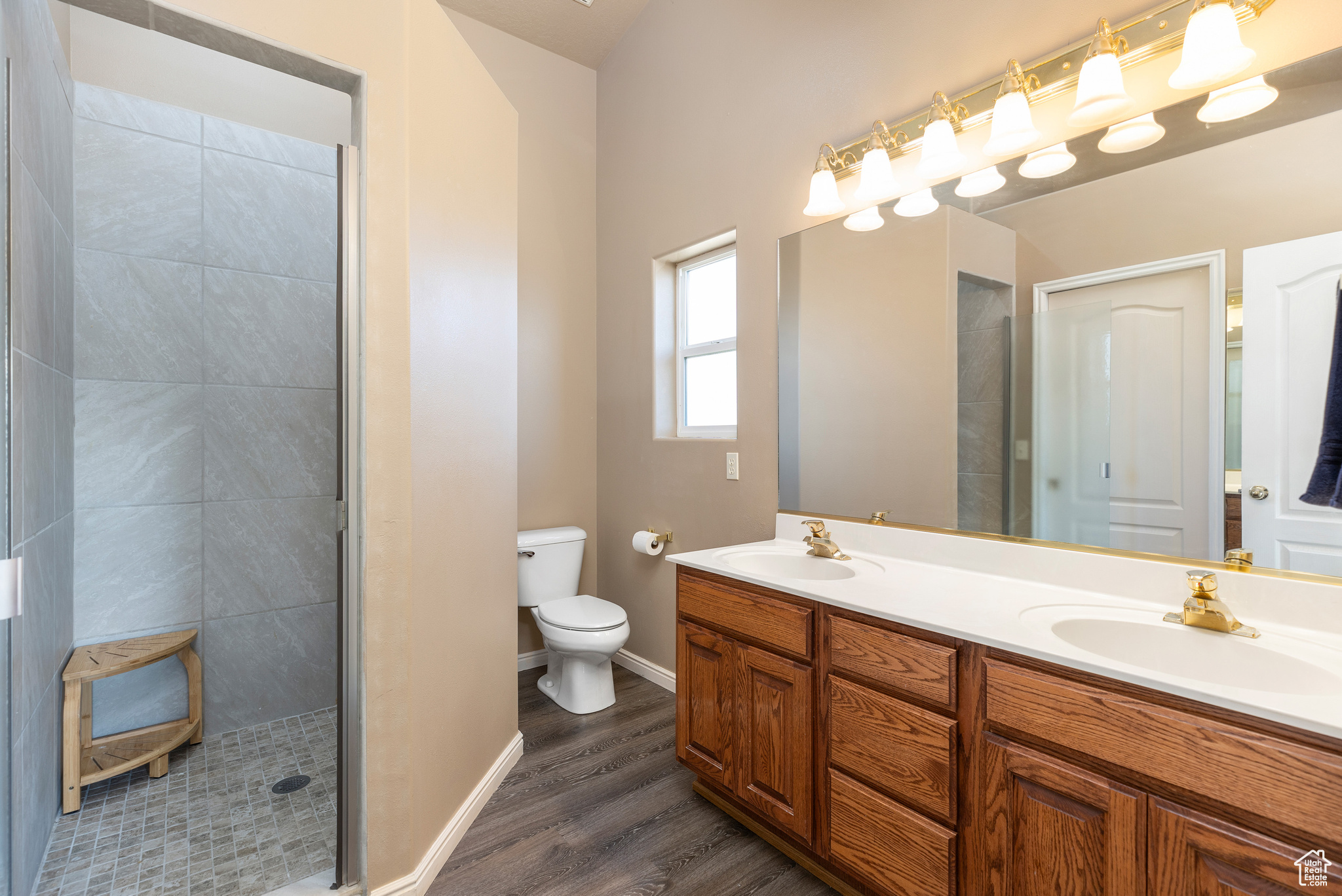 Bathroom featuring wood-type flooring, toilet, walk in shower, and vanity