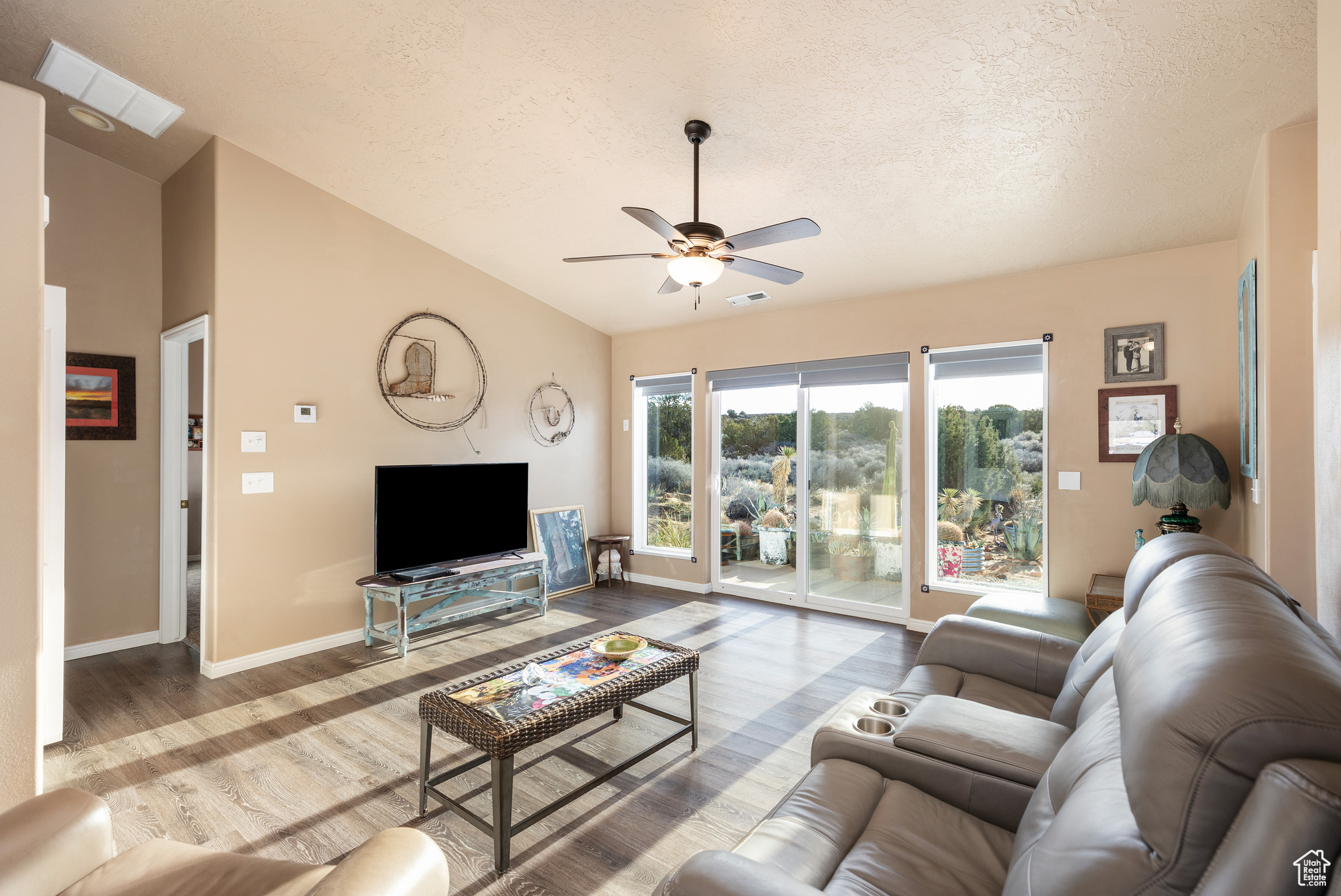 Living room featuring lofted ceiling, wood-type flooring, a textured ceiling, and ceiling fan