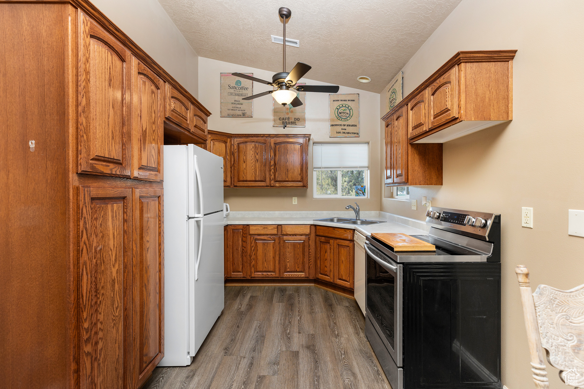 Kitchen with dark hardwood / wood-style floors, white fridge, sink, stainless steel electric stove, and a textured ceiling