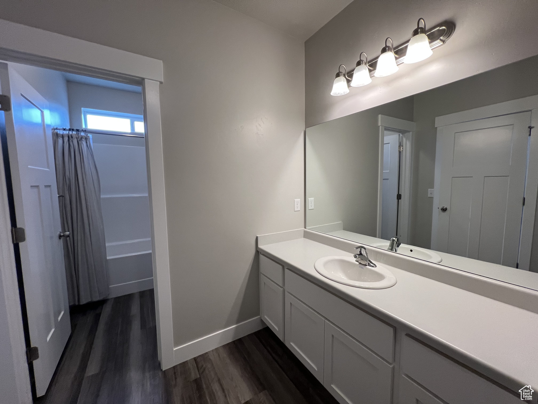 Bathroom with hardwood / wood-style flooring, vanity, and shower / tub combo