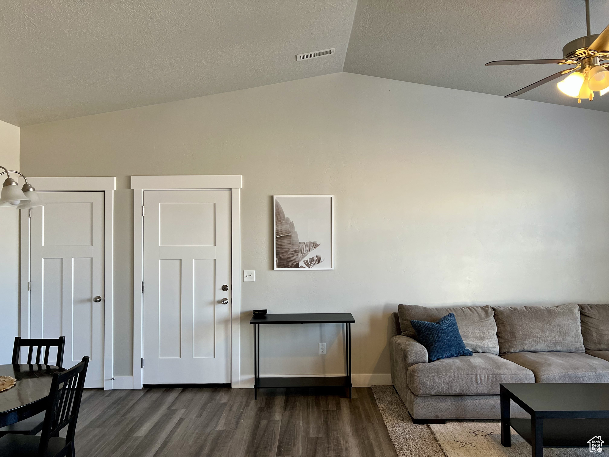 Living room with ceiling fan, a textured ceiling, dark hardwood / wood-style flooring, and lofted ceiling