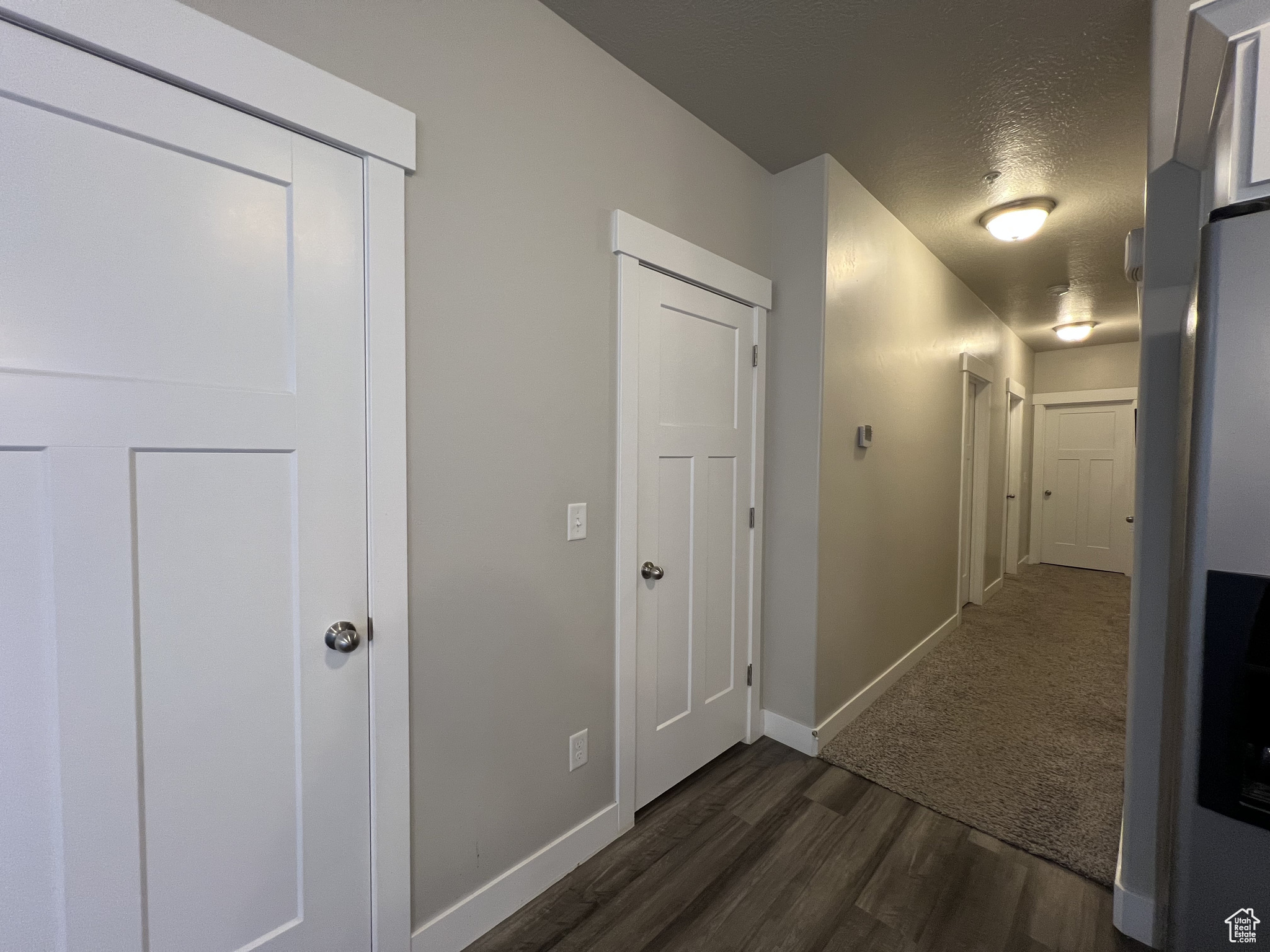 Hall with a textured ceiling and dark hardwood / wood-style floors