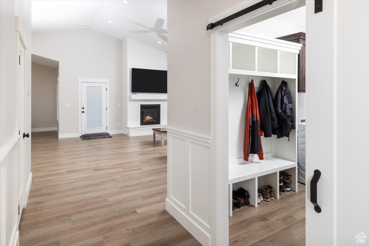 Mudroom featuring lofted ceiling, ceiling fan, a fireplace, and light hardwood / wood-style flooring