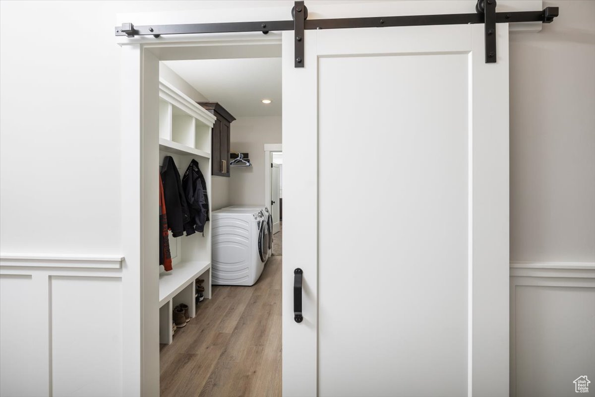 Mudroom featuring light hardwood / wood-style flooring, independent washer and dryer, and a barn door