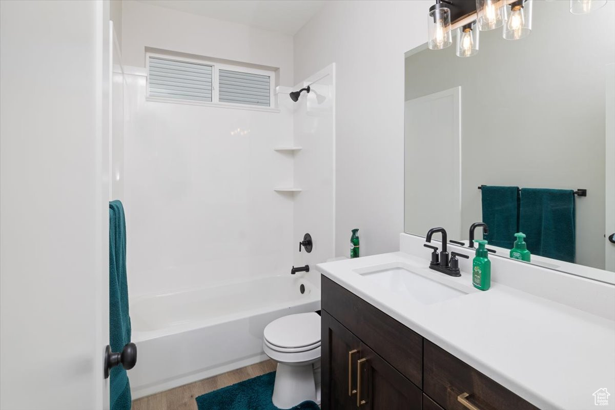 Full bathroom with toilet, vanity, washtub / shower combination, and hardwood / wood-style flooring