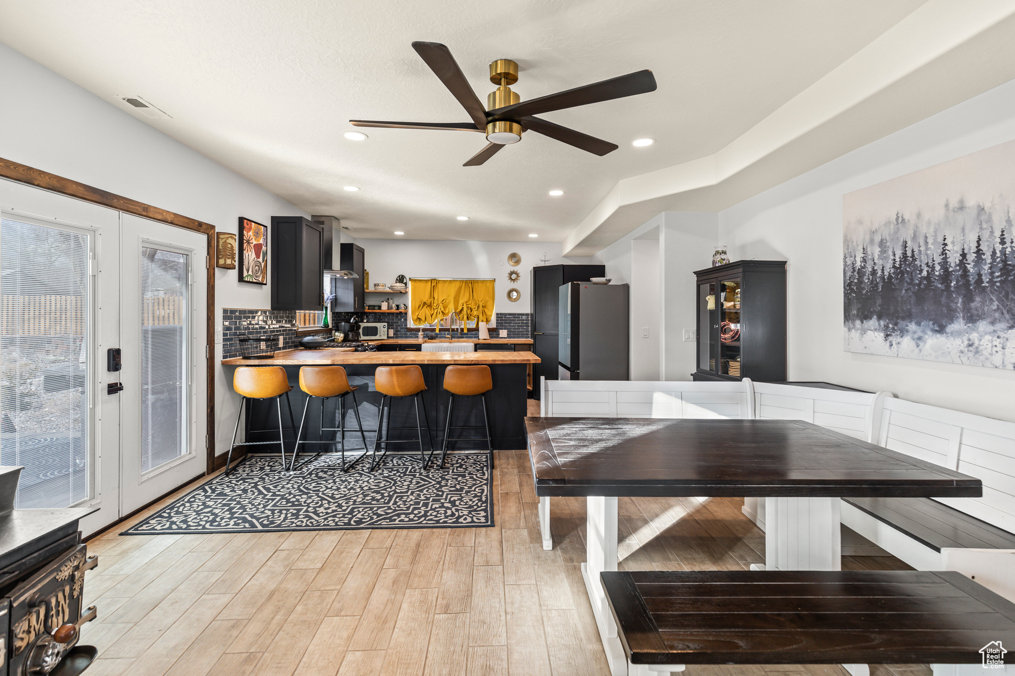 Kitchen with french doors, stainless steel fridge, kitchen peninsula, light wood-type flooring, and ceiling fan