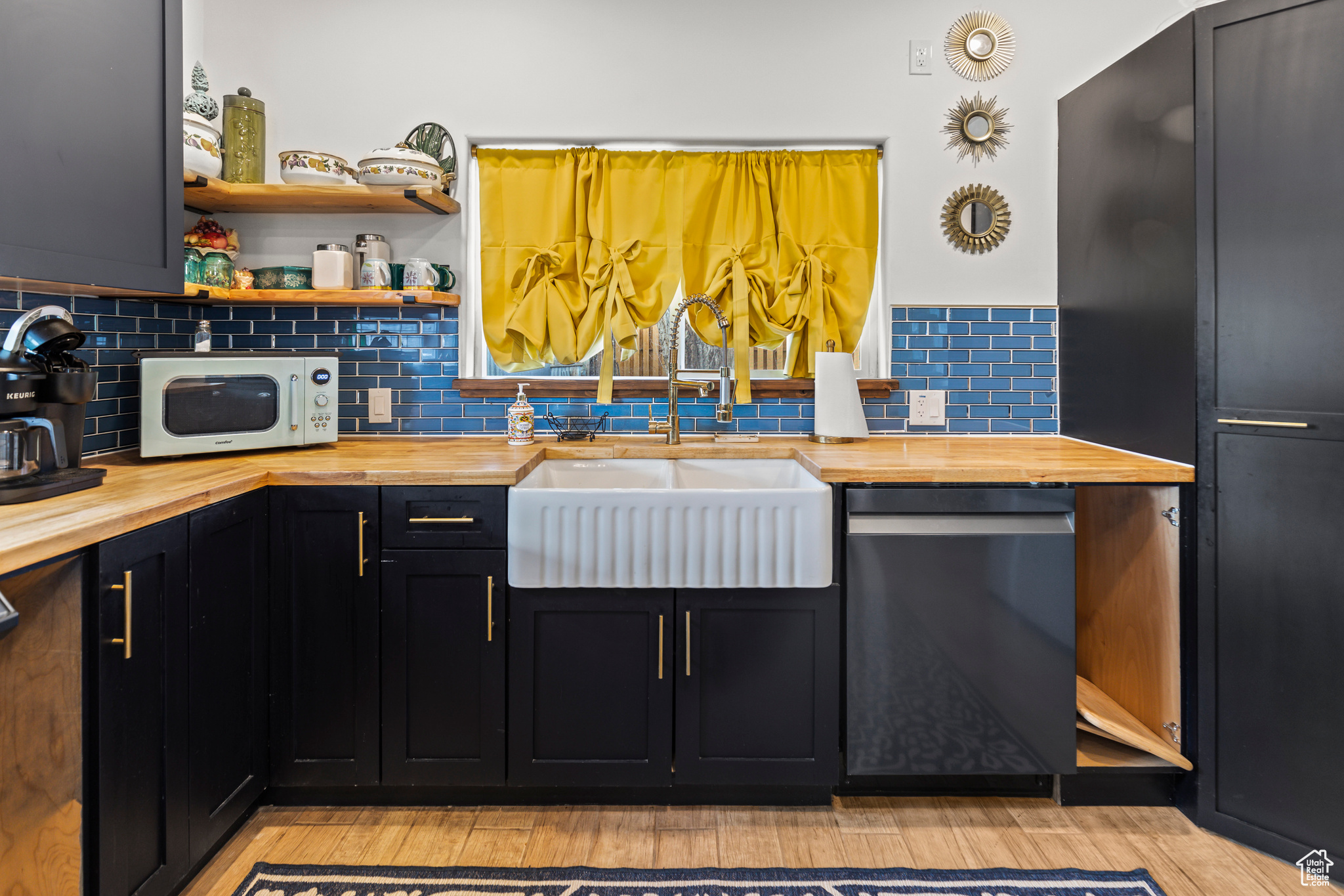 Kitchen with decorative backsplash, sink, black dishwasher, and butcher block counters