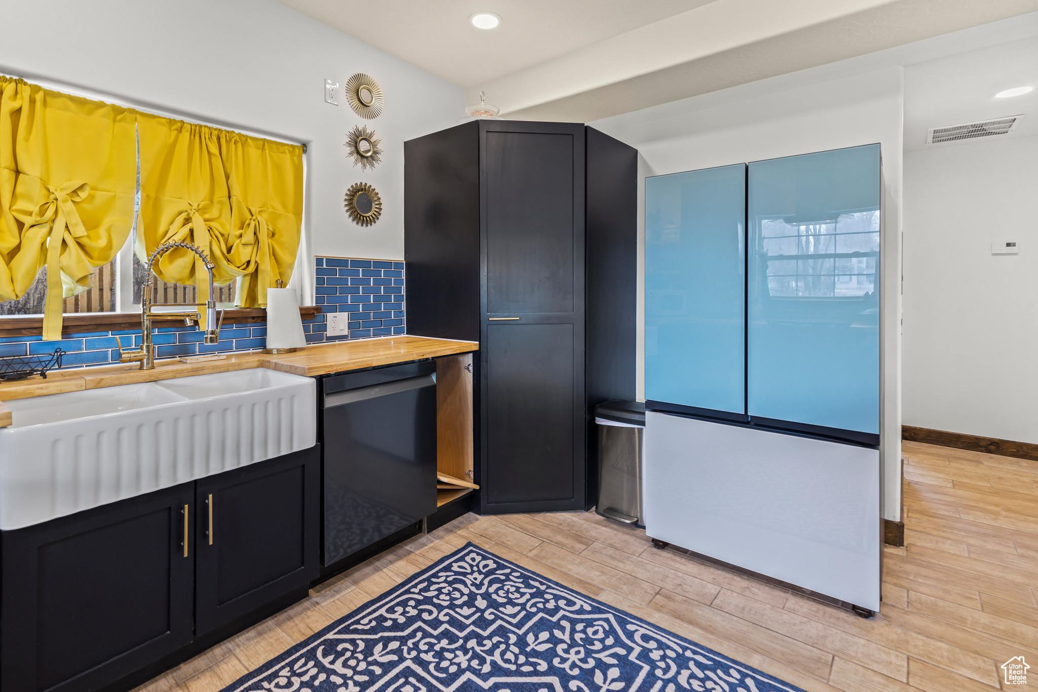 Kitchen with sink, black dishwasher, wooden counters, and fridge