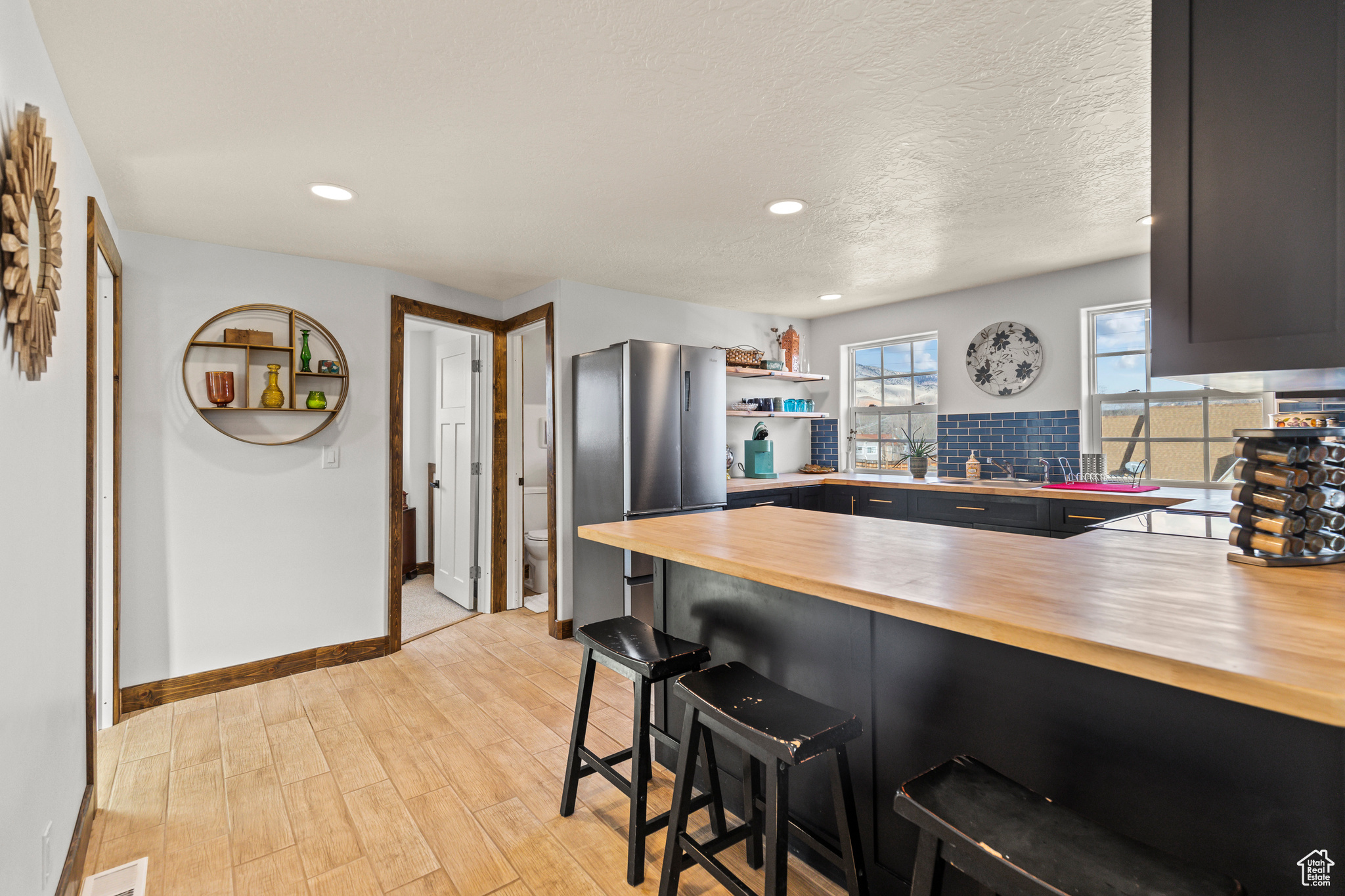 Kitchen with wooden counters, a kitchen breakfast bar, stainless steel fridge, kitchen peninsula, and light hardwood / wood-style flooring