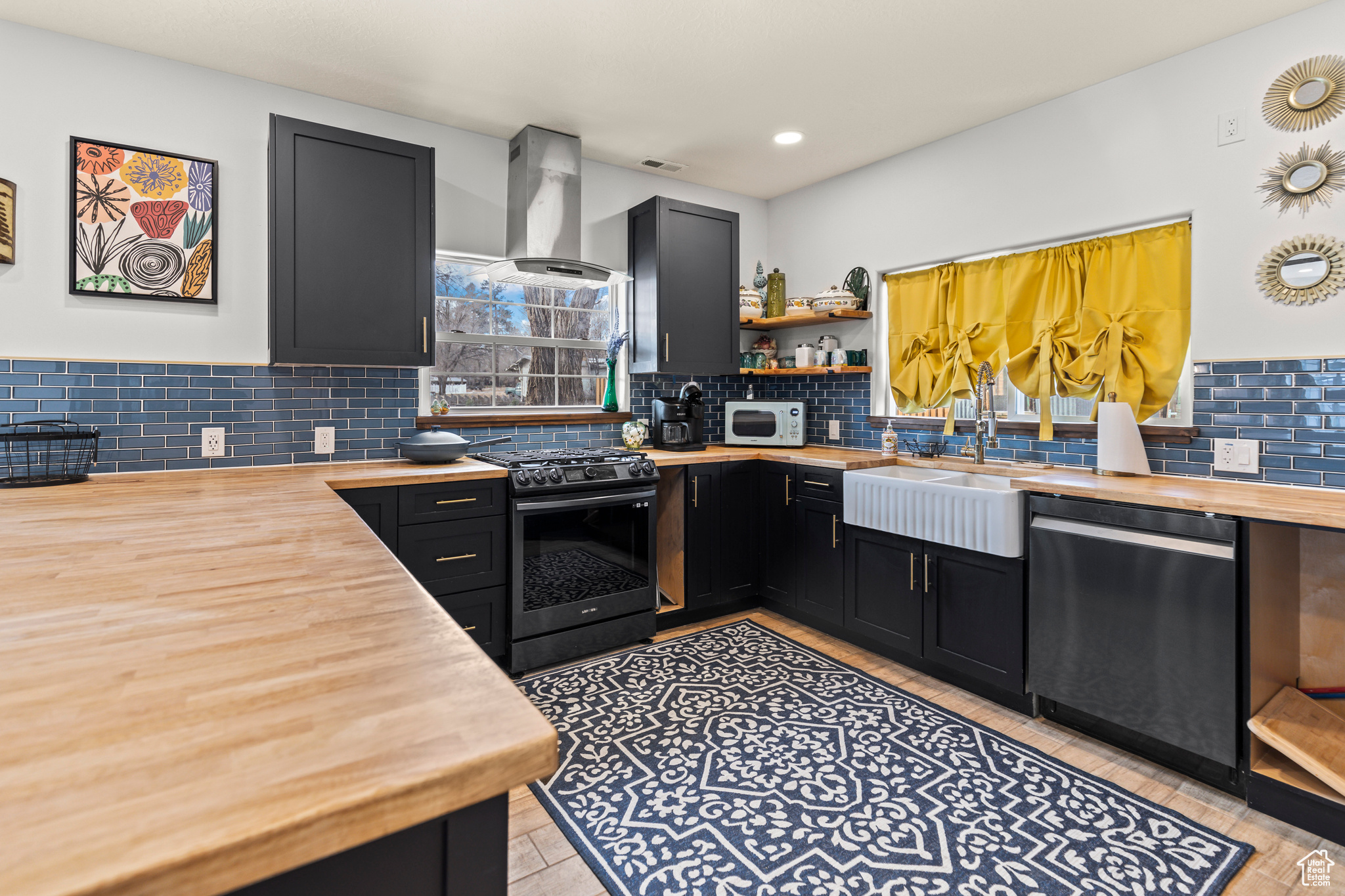 Kitchen with dishwashing machine, exhaust hood, wooden counters, sink, and gas range oven