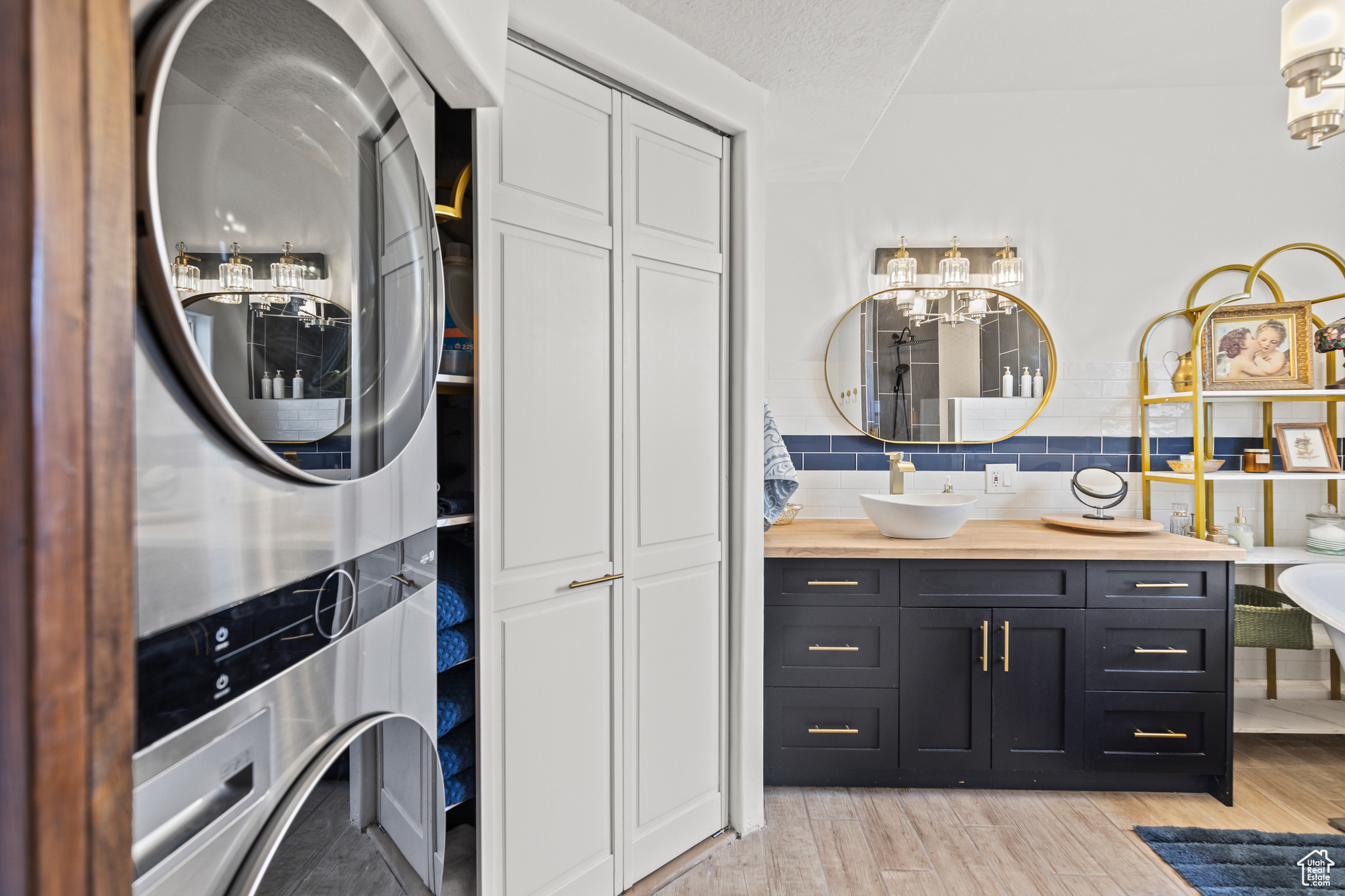 Laundry area featuring a textured ceiling, stacked washer / dryer, and sink