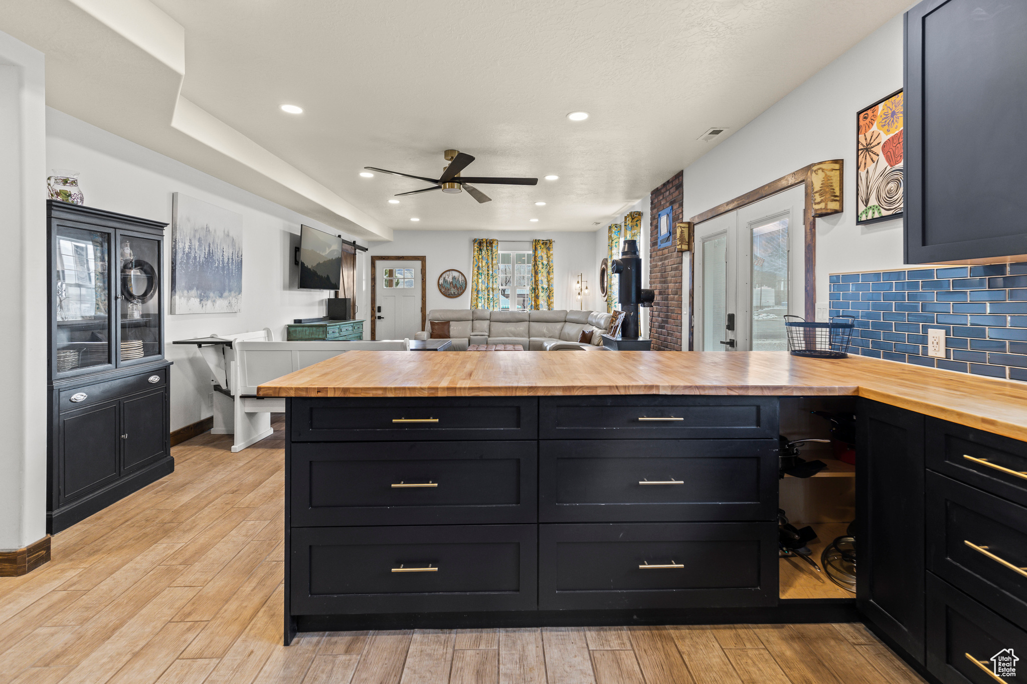 Kitchen with wood counters, light hardwood / wood-style floors, backsplash, kitchen peninsula, and ceiling fan