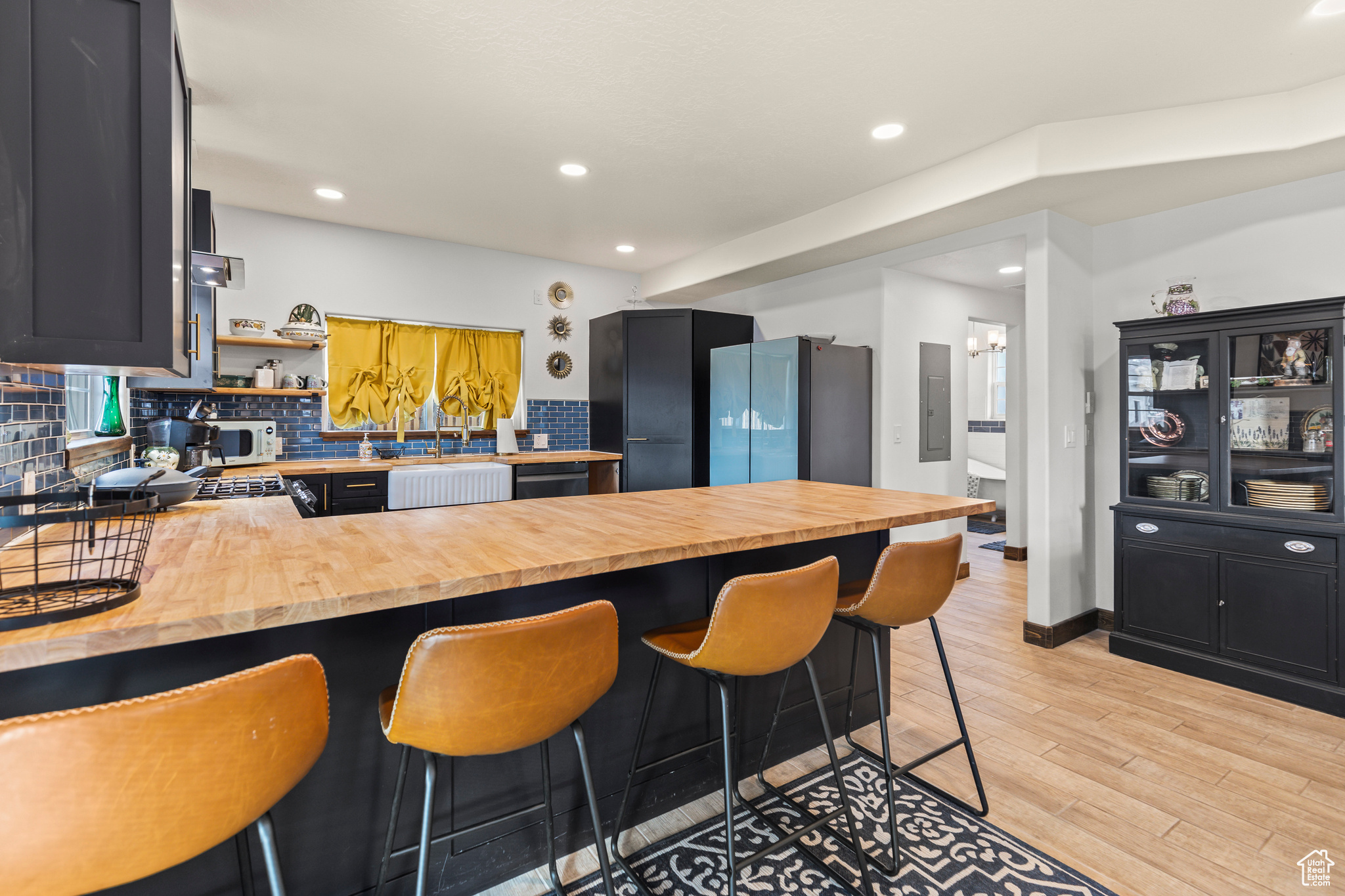 Kitchen with wood counters, kitchen peninsula, a breakfast bar area, decorative backsplash, and light wood-type flooring