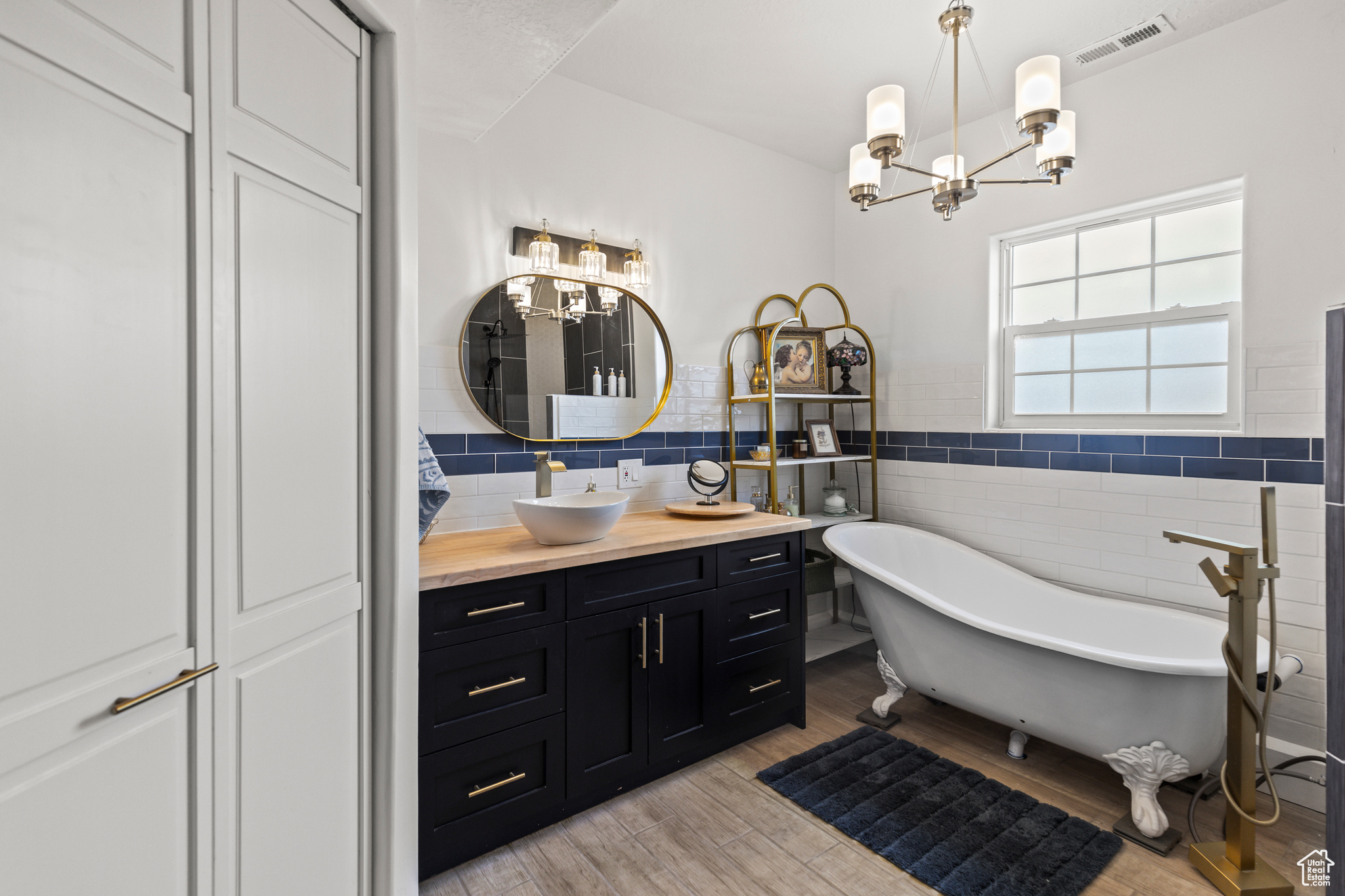 Bathroom with a bathing tub, tile walls, vanity, and a notable chandelier