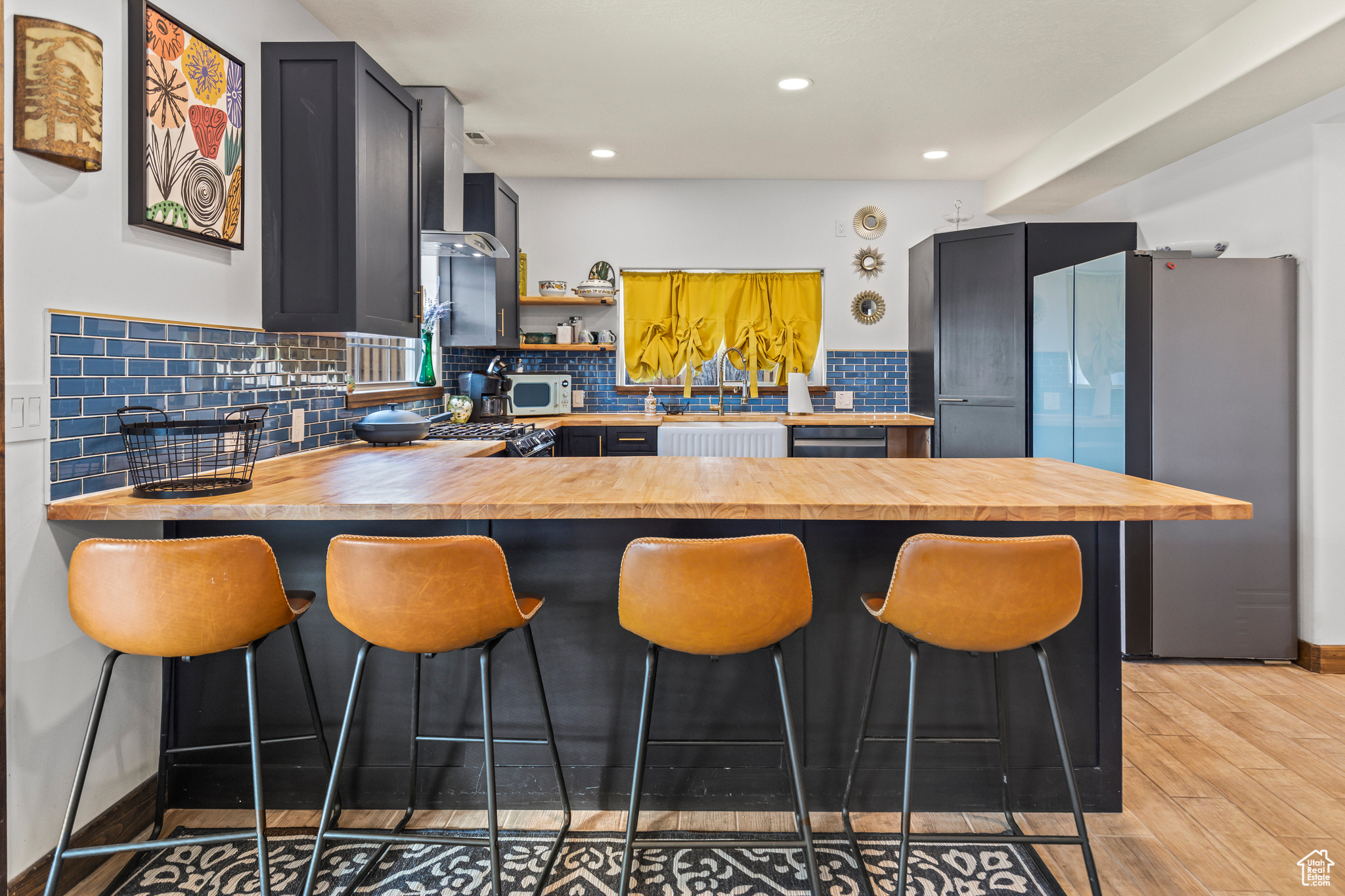 Kitchen featuring light hardwood / wood-style flooring, a kitchen bar, kitchen peninsula, and wooden counters