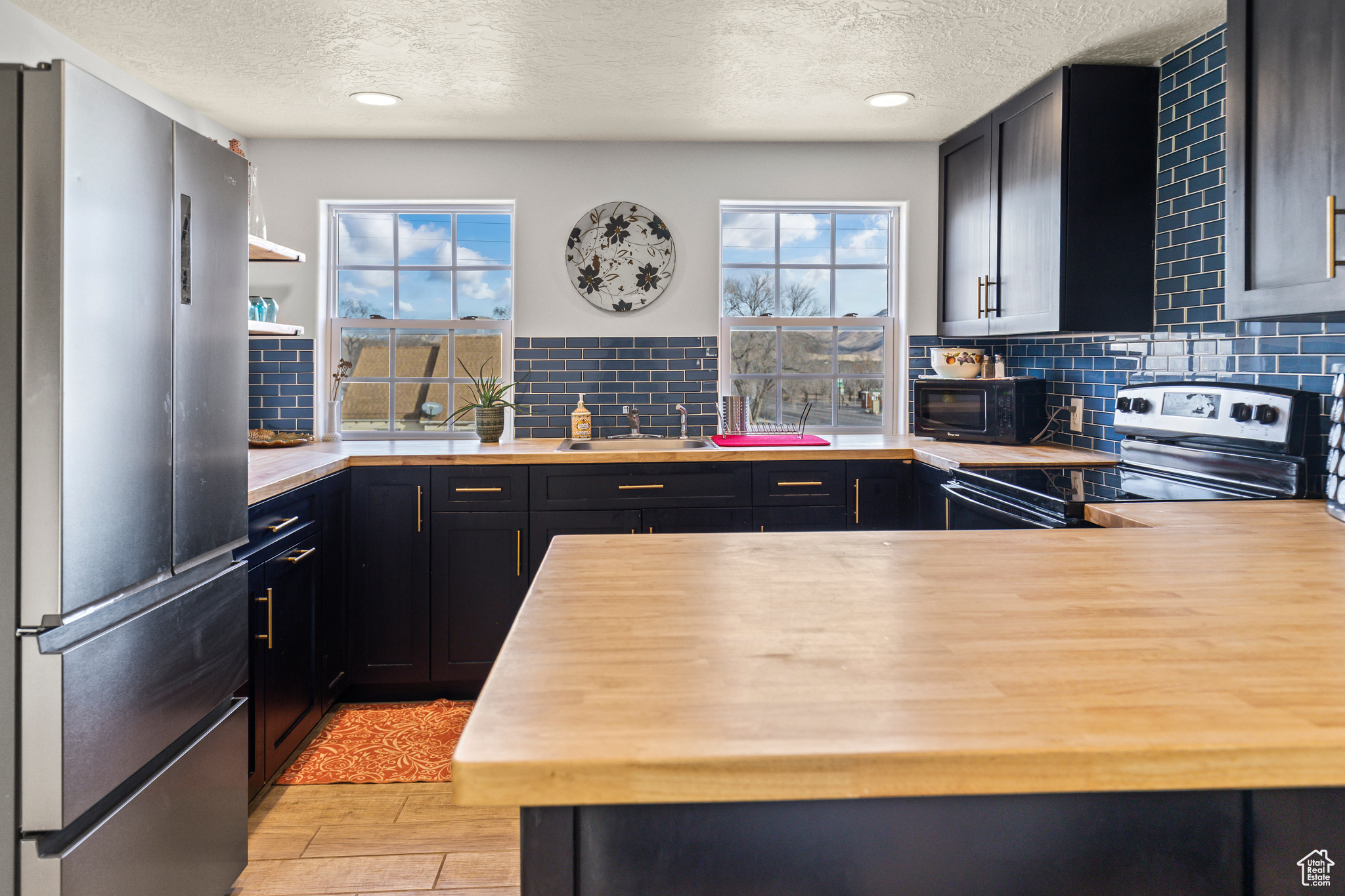 Kitchen featuring light wood-type flooring, stainless steel appliances, tasteful backsplash, and sink