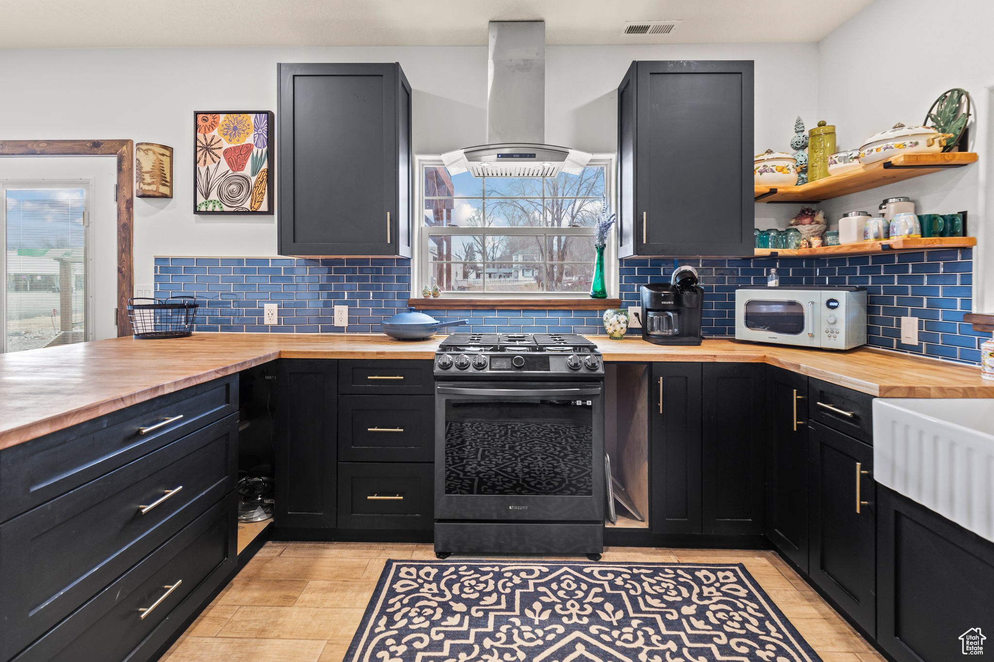 Kitchen with island exhaust hood, a healthy amount of sunlight, gas range, and butcher block countertops