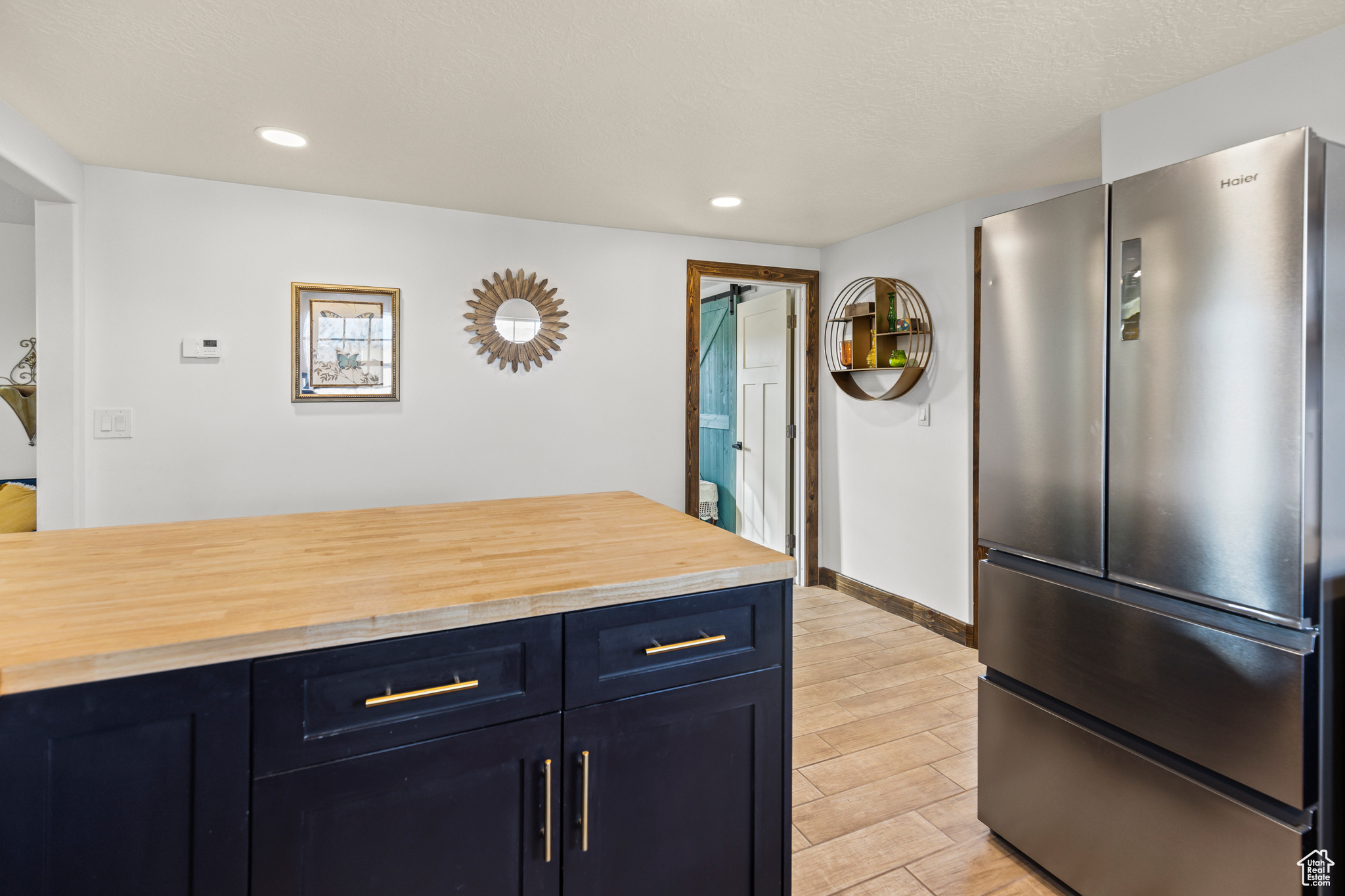 Kitchen with blue cabinetry, stainless steel fridge, and wooden counters