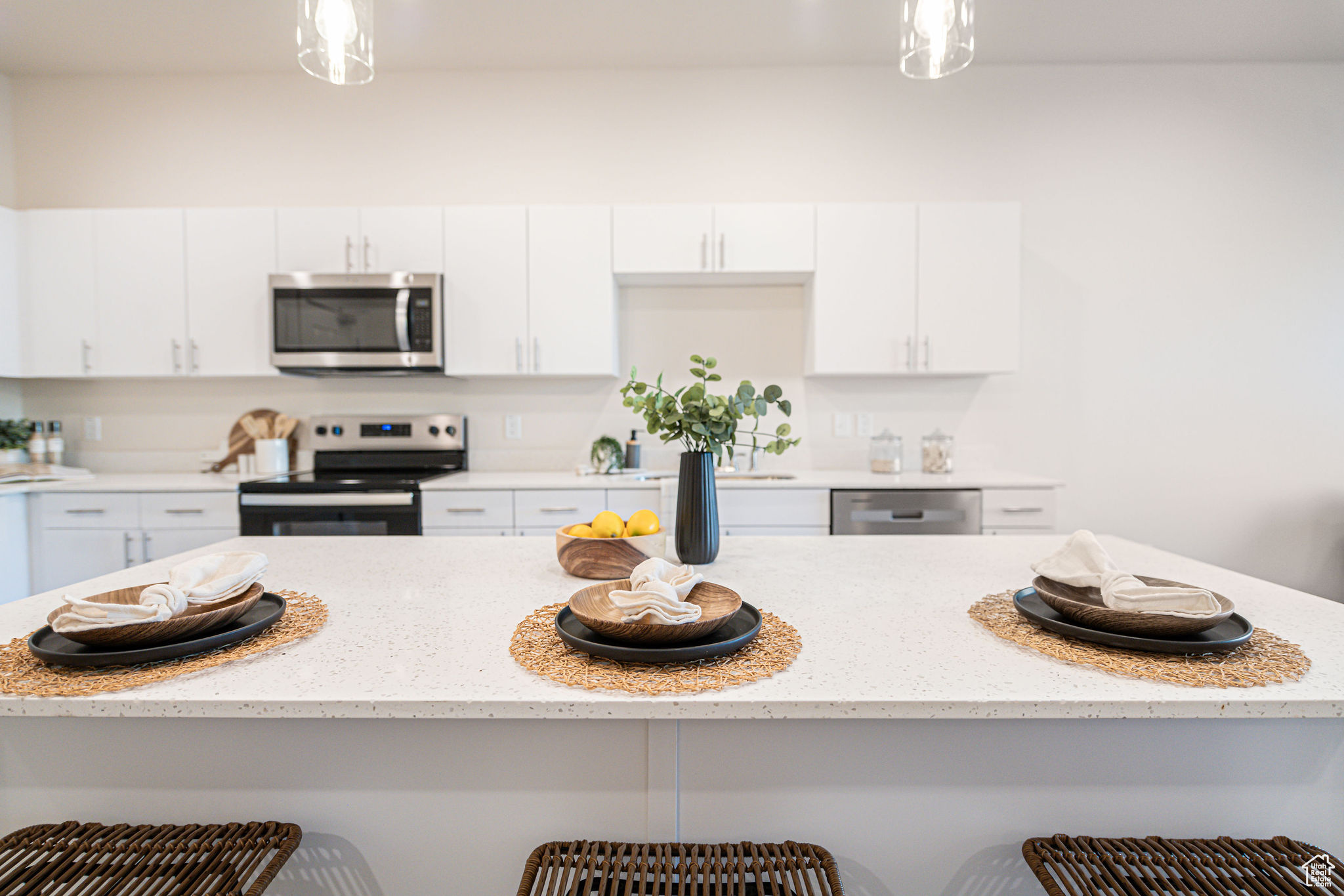 Kitchen featuring stainless steel appliances, pendant lighting, white cabinetry, and a breakfast bar