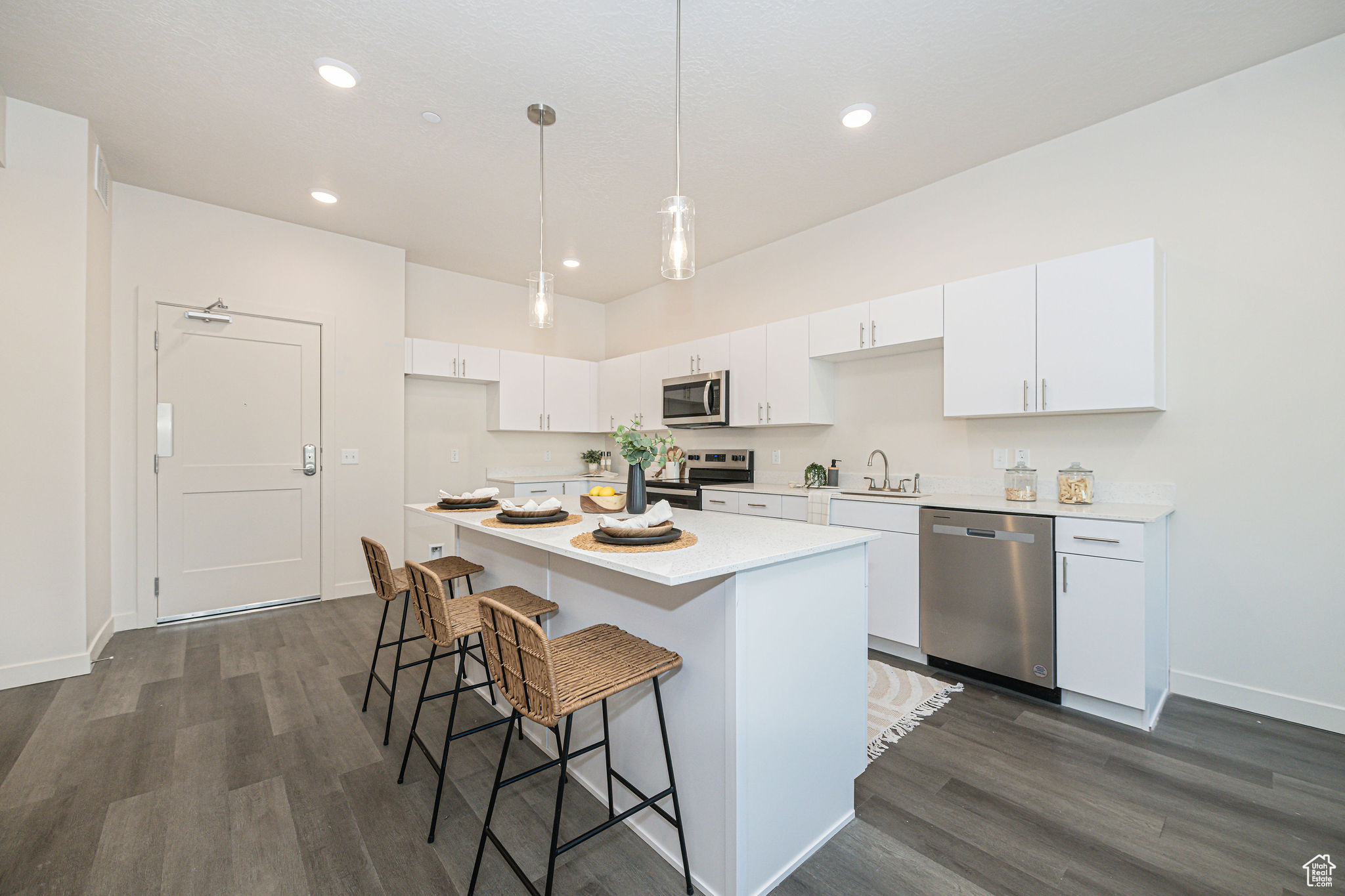 Kitchen featuring dark wood-type flooring, stainless steel appliances, white cabinetry, and a kitchen island