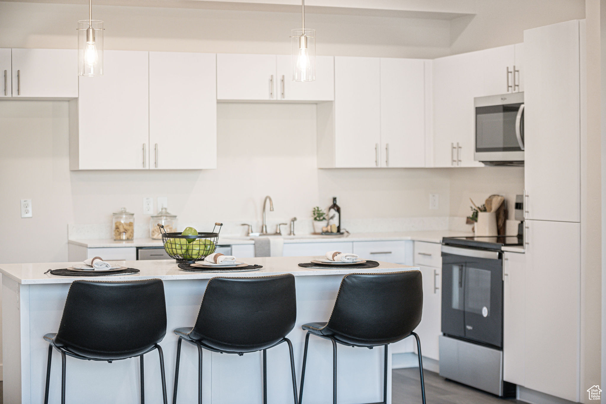 Kitchen with appliances with stainless steel finishes, pendant lighting, white cabinets, and a kitchen island