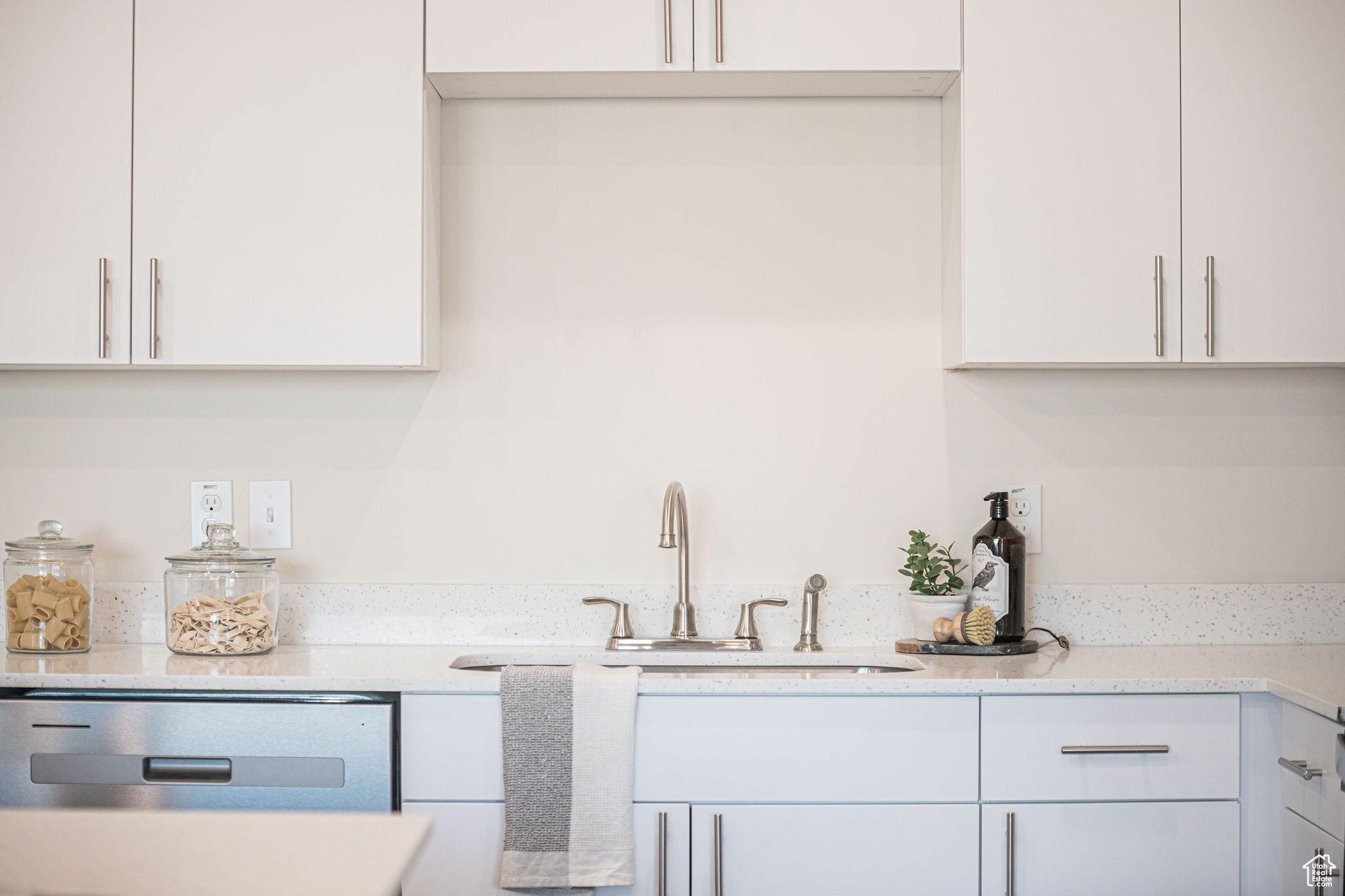 Kitchen with white cabinetry, dishwasher, and sink