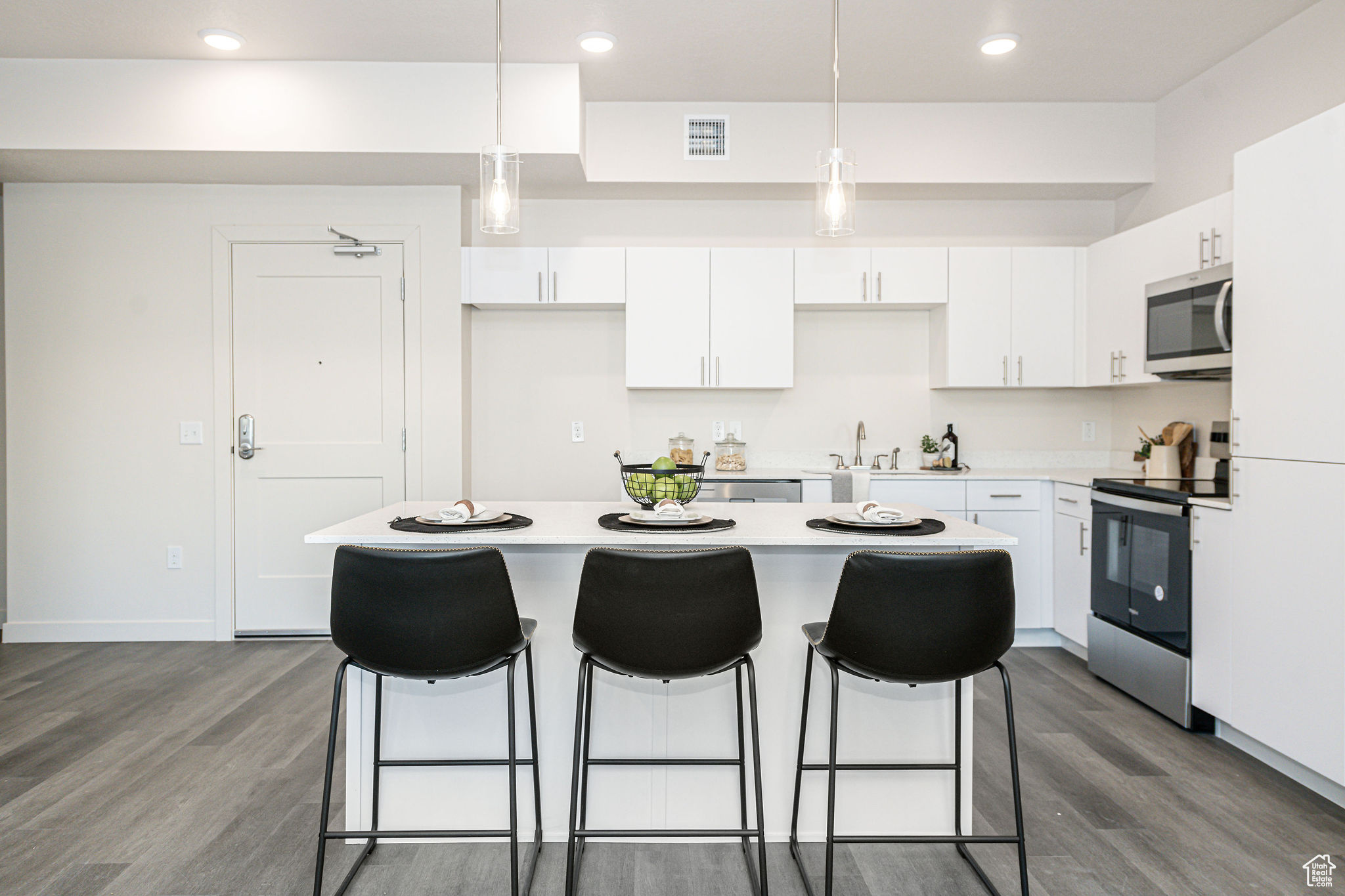 Kitchen featuring pendant lighting, white cabinetry, a center island, and stainless steel appliances