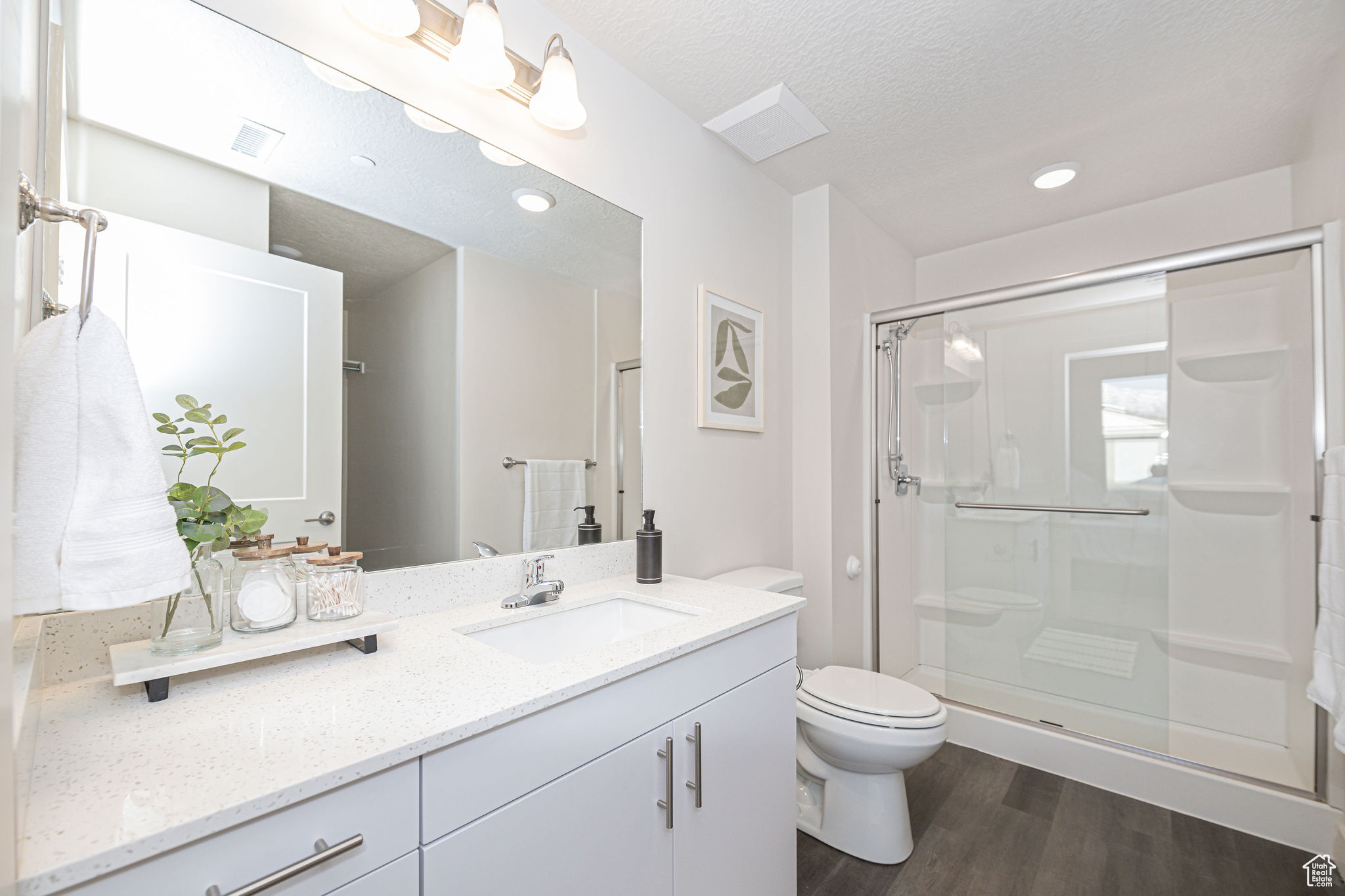 Bathroom featuring toilet, hardwood / wood-style floors, a shower with door, a textured ceiling, and vanity