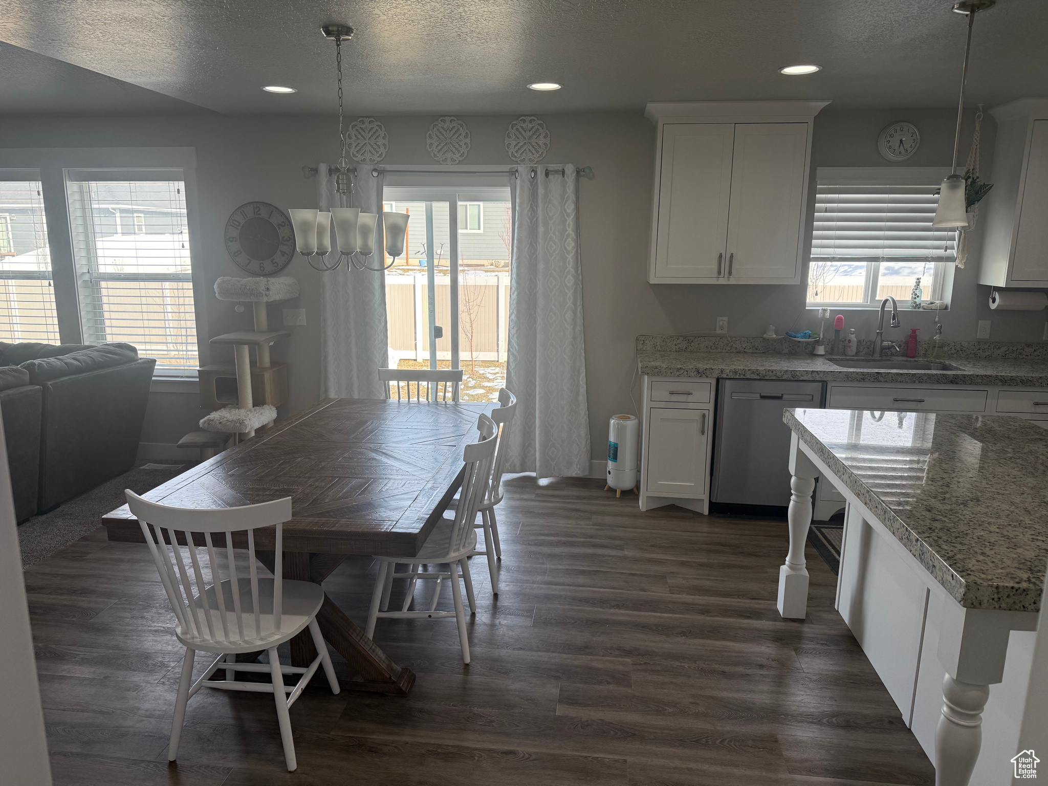 Kitchen featuring decorative light fixtures, sink, white cabinets, and dishwasher