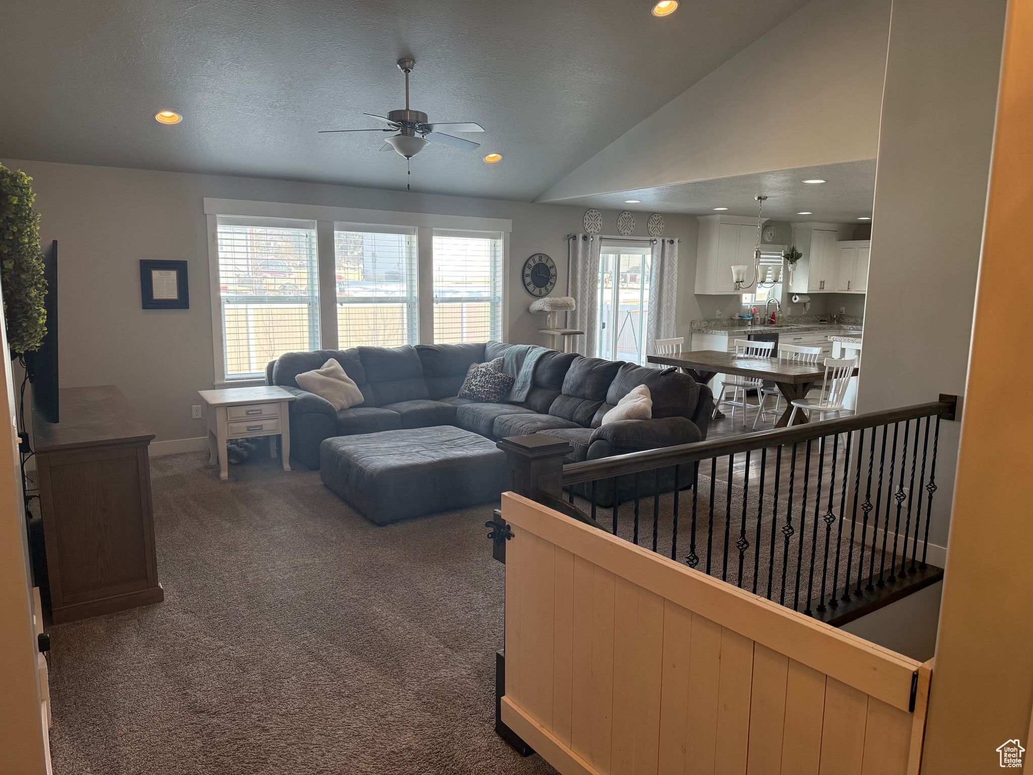 Living room with dark colored carpet, sink, ceiling fan, and vaulted ceiling