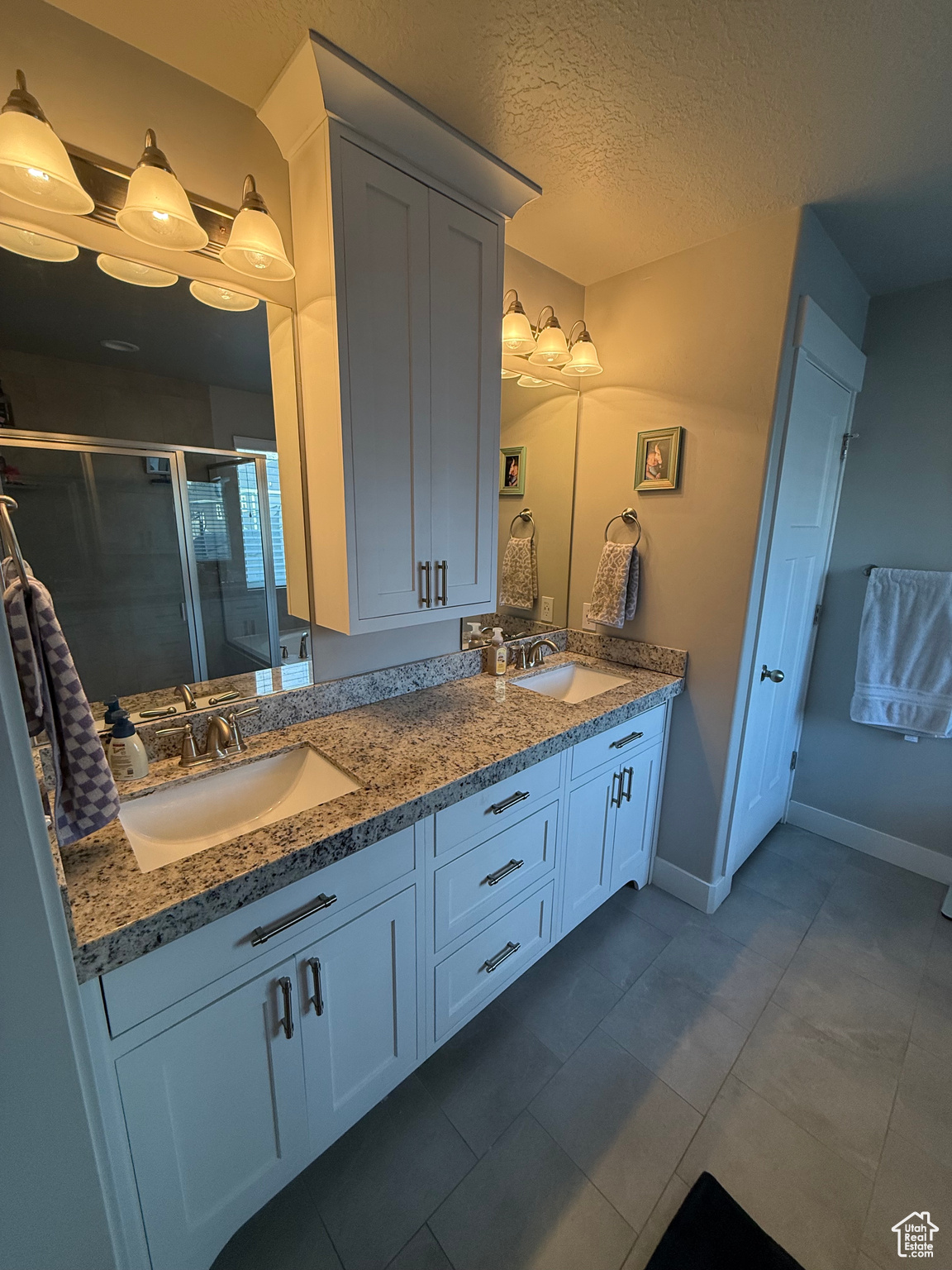 Bathroom featuring a textured ceiling, tile patterned floors, an enclosed shower, and vanity