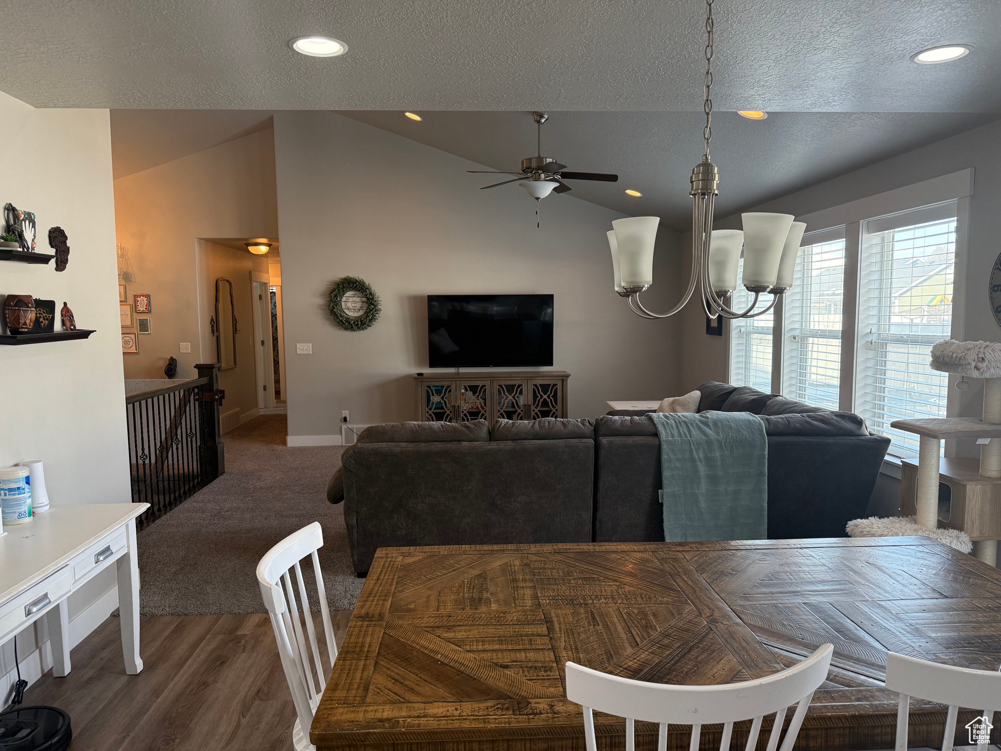 Dining room with a textured ceiling, dark hardwood / wood-style flooring, lofted ceiling, and ceiling fan with notable chandelier