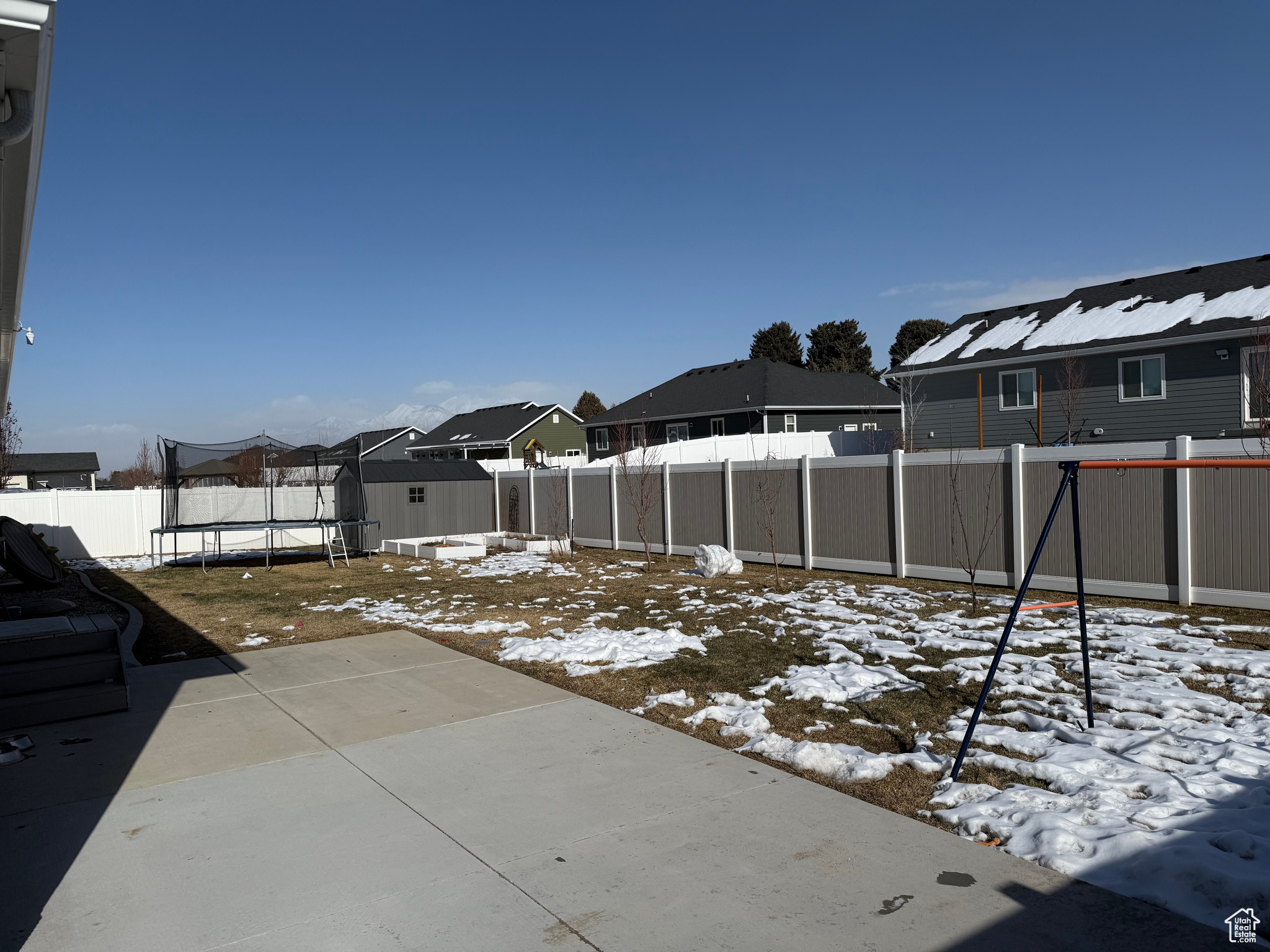 Snowy yard featuring a trampoline and a storage unit