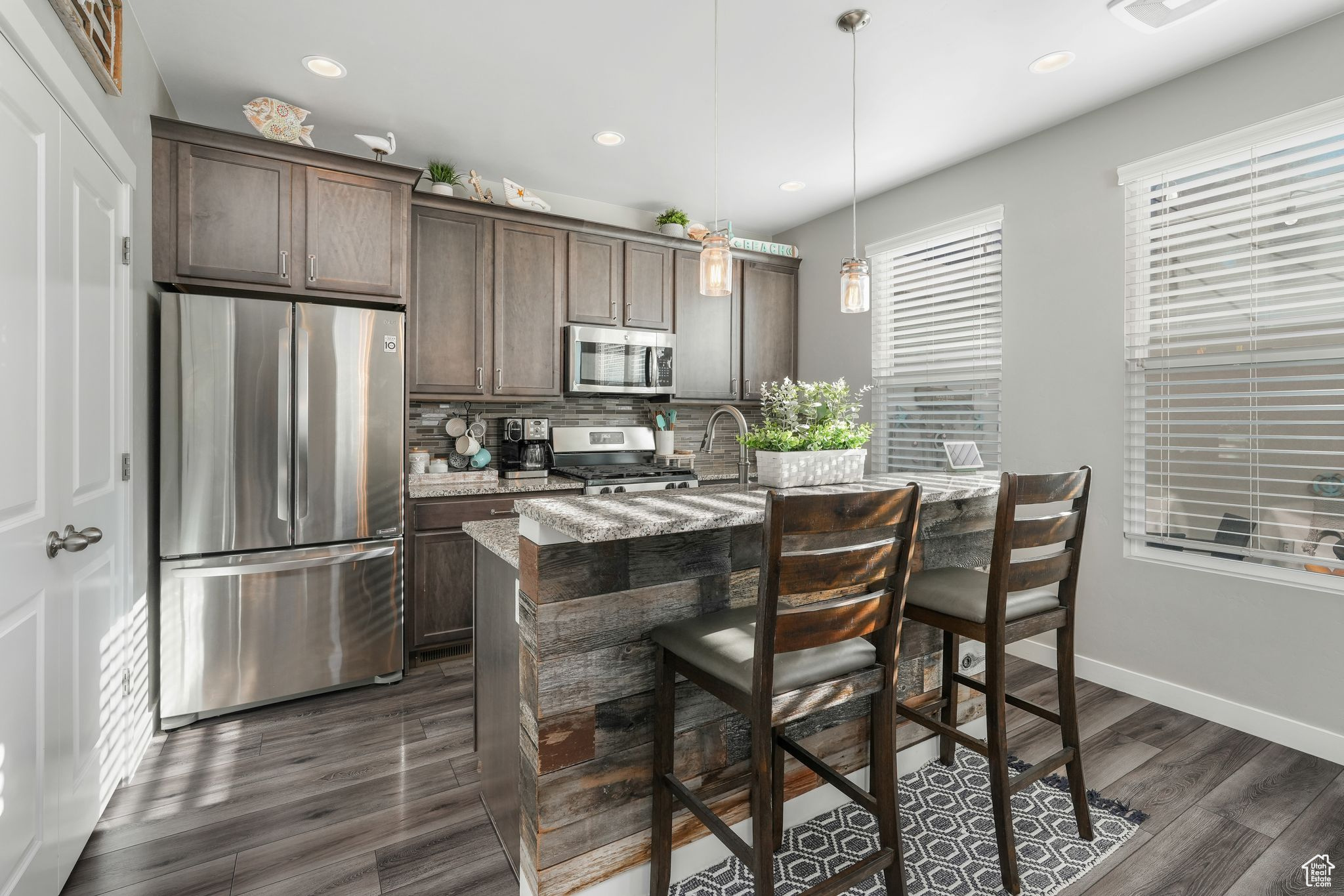 Kitchen with light stone counters, dark brown cabinetry, and appliances with stainless steel finishes