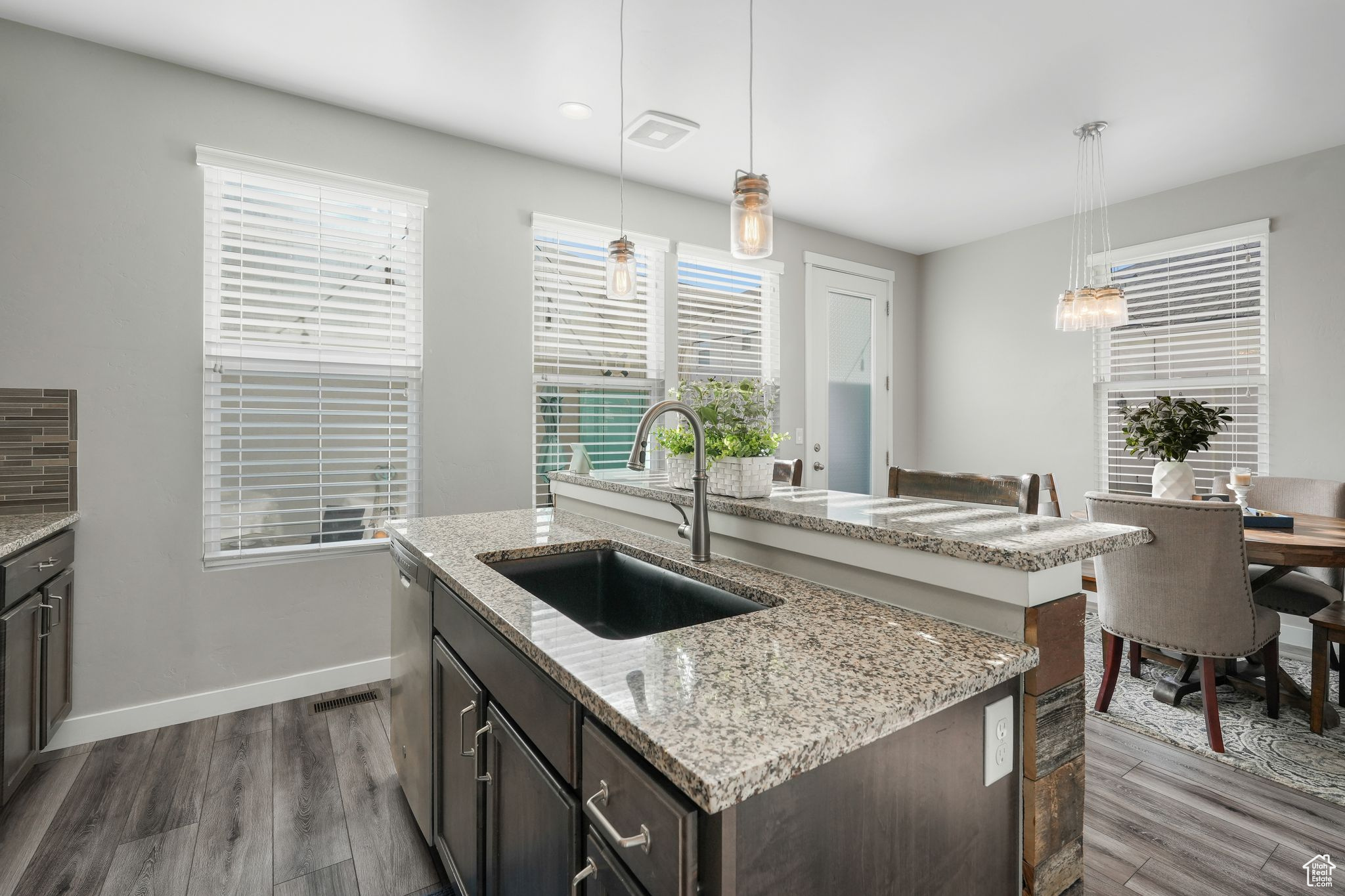 Kitchen featuring a kitchen island with sink, decorative light fixtures, dark wood-type flooring, dark brown cabinetry, and sink