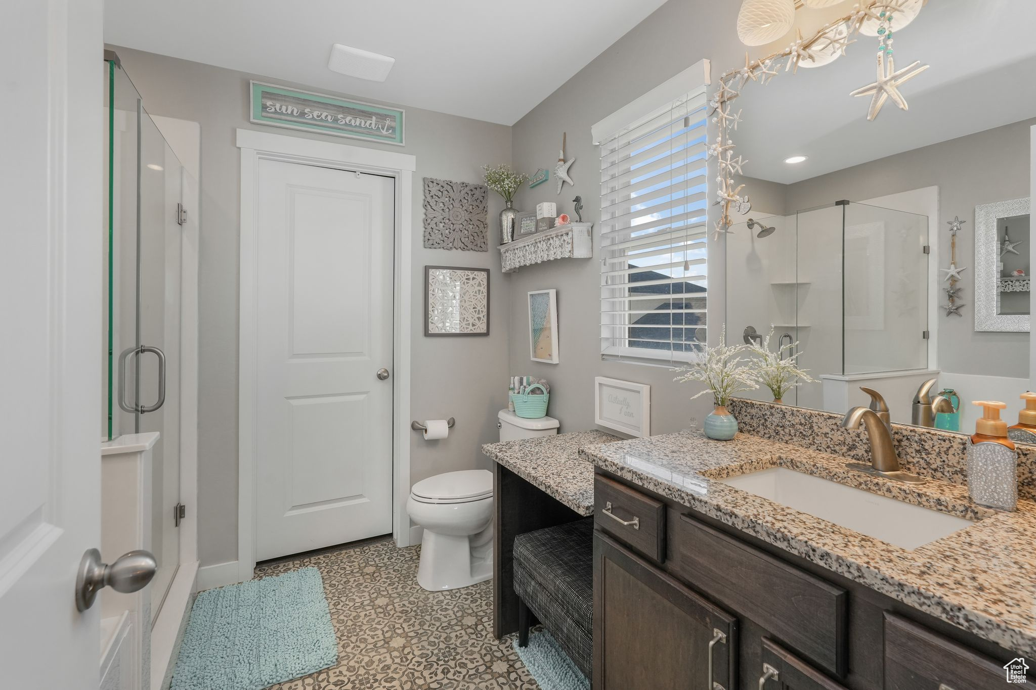 Bathroom featuring a shower with shower door, vanity, and toilet