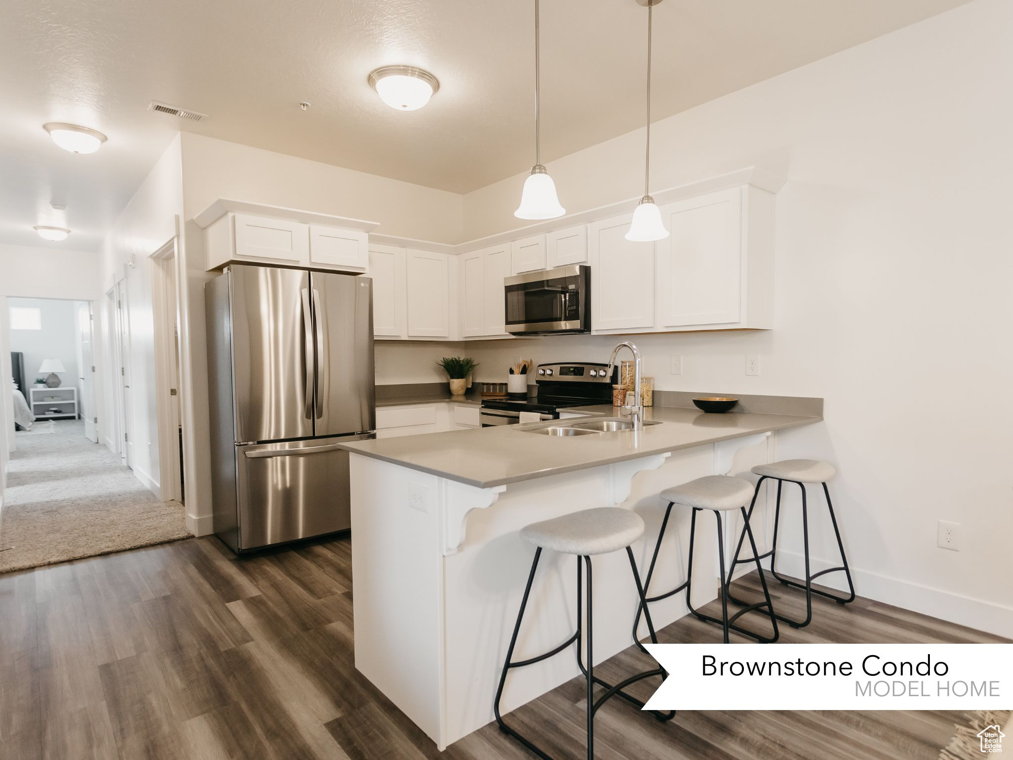 Kitchen with kitchen peninsula, stainless steel appliances, white cabinets, and decorative light fixtures