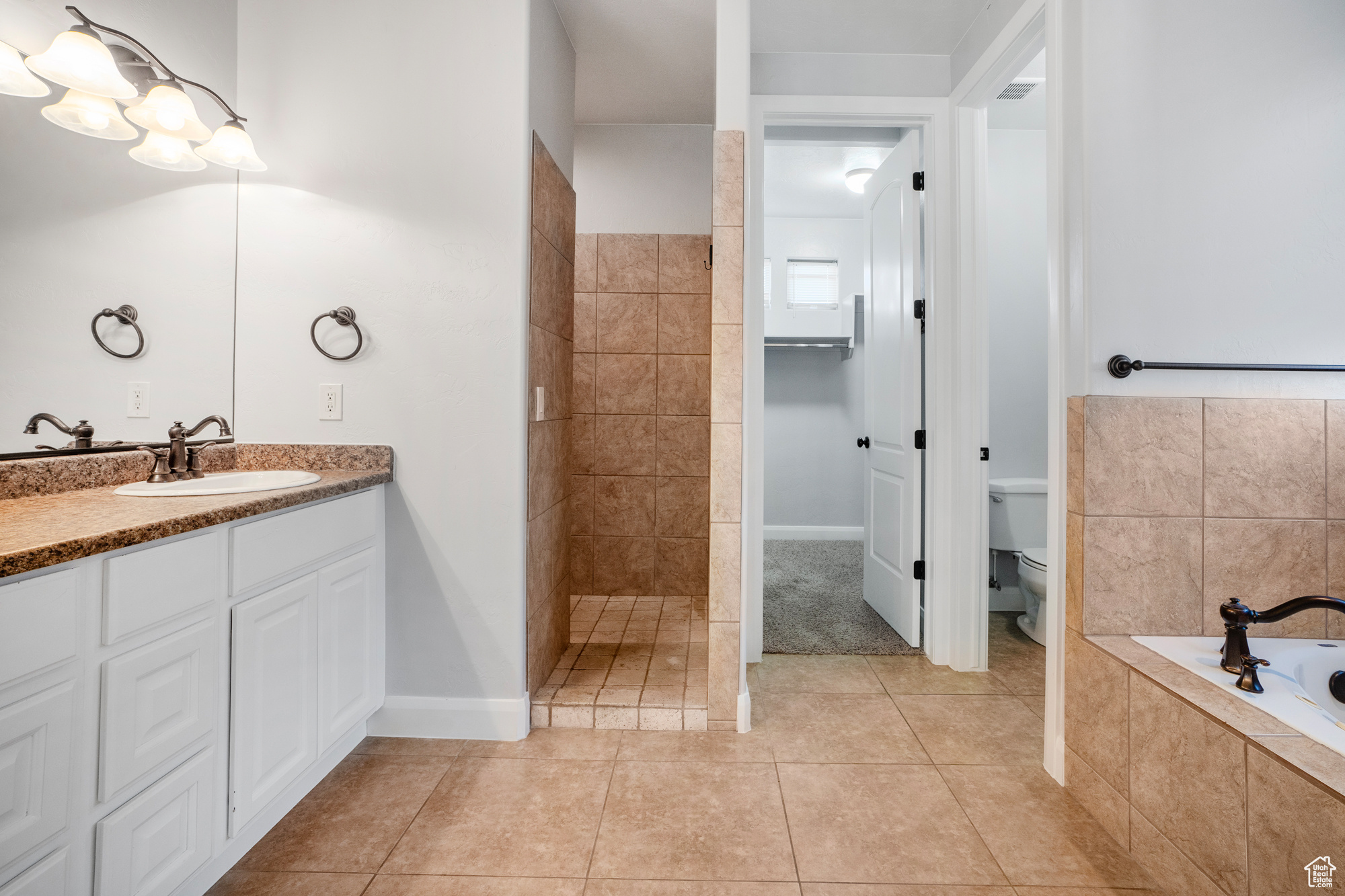 Full bathroom featuring tile patterned floors, vanity, toilet, and shower with separate bathtub