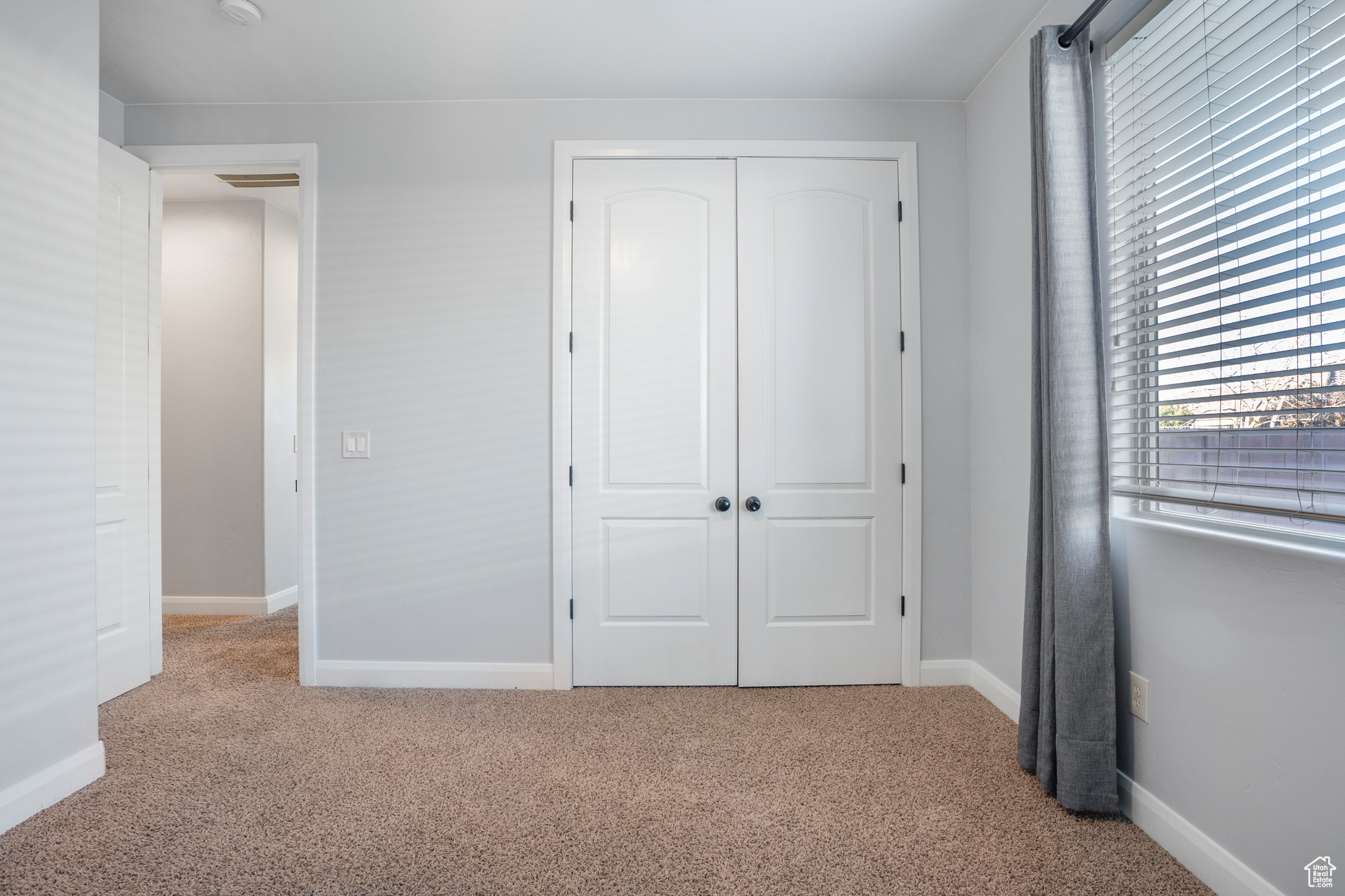 Unfurnished bedroom with light colored carpet and a closet