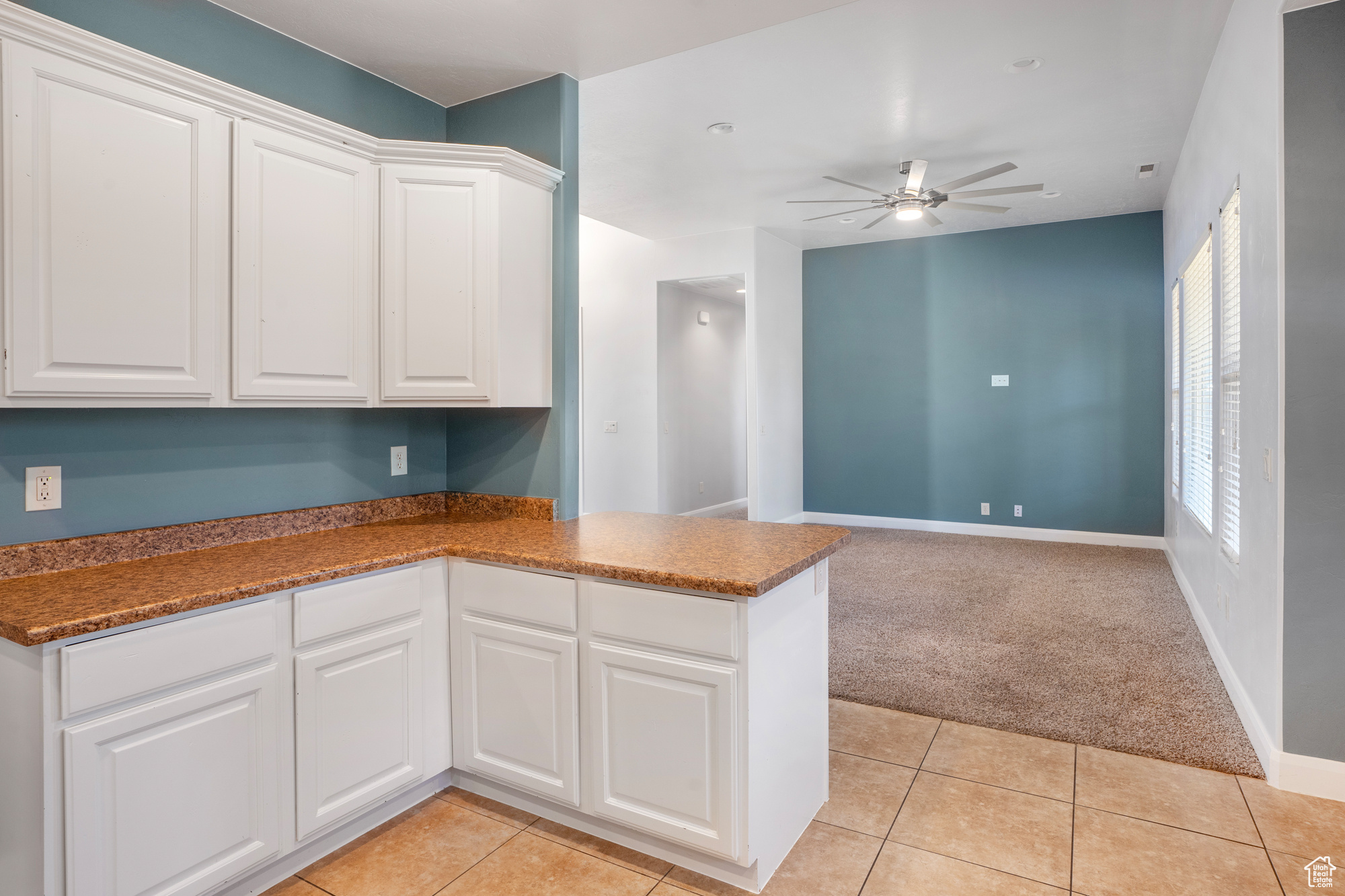 Kitchen featuring white cabinets, kitchen peninsula, and light tile patterned flooring