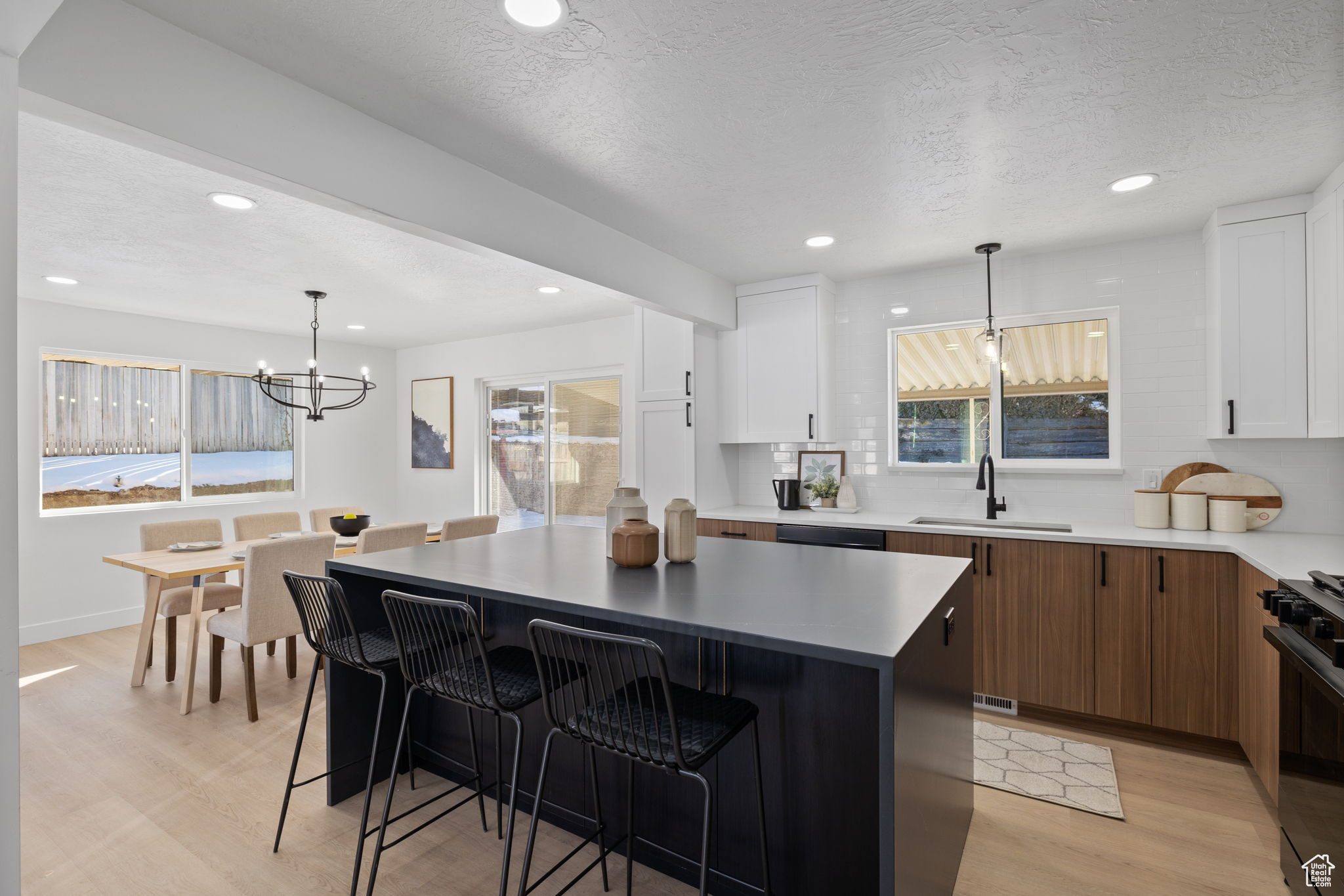 Kitchen with light hardwood / wood-style floors, white cabinetry, a center island, and black gas range oven