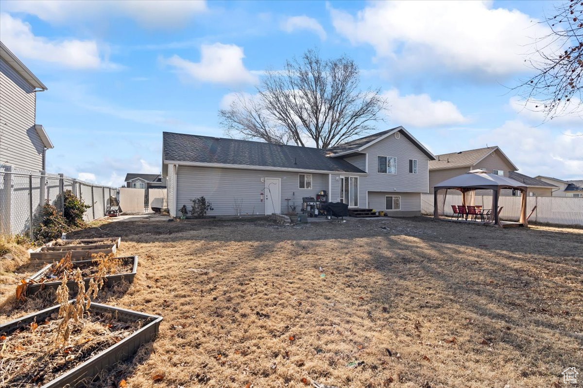 Back of house featuring a gazebo and a yard