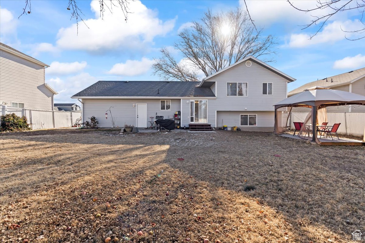 Rear view of house with a gazebo and a yard