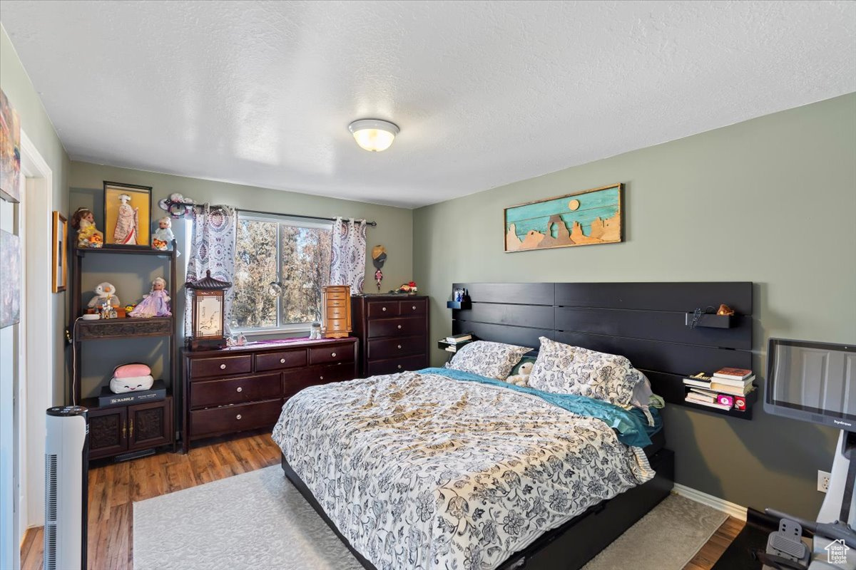 Bedroom with light hardwood / wood-style floors and a textured ceiling